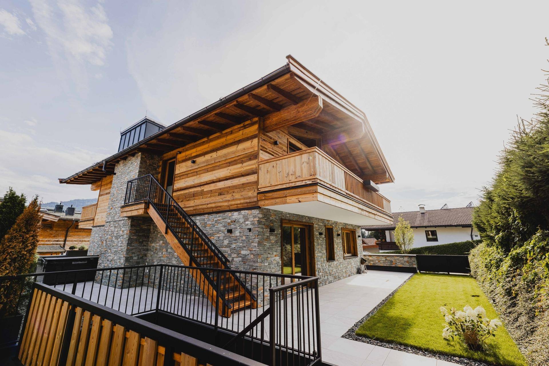 Attraktives Chalet mit Holz- und Steinfassade, umgeben von einem gepflegten Garten und einer sonnigen Terrasse.