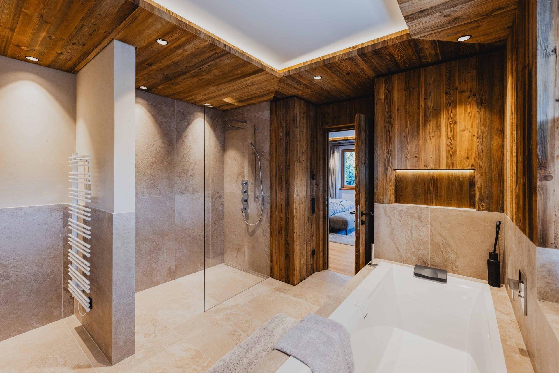 Geräumiges Badezimmer mit begehbarer Dusche, Badewanne und beheiztem Handtuchhalter.