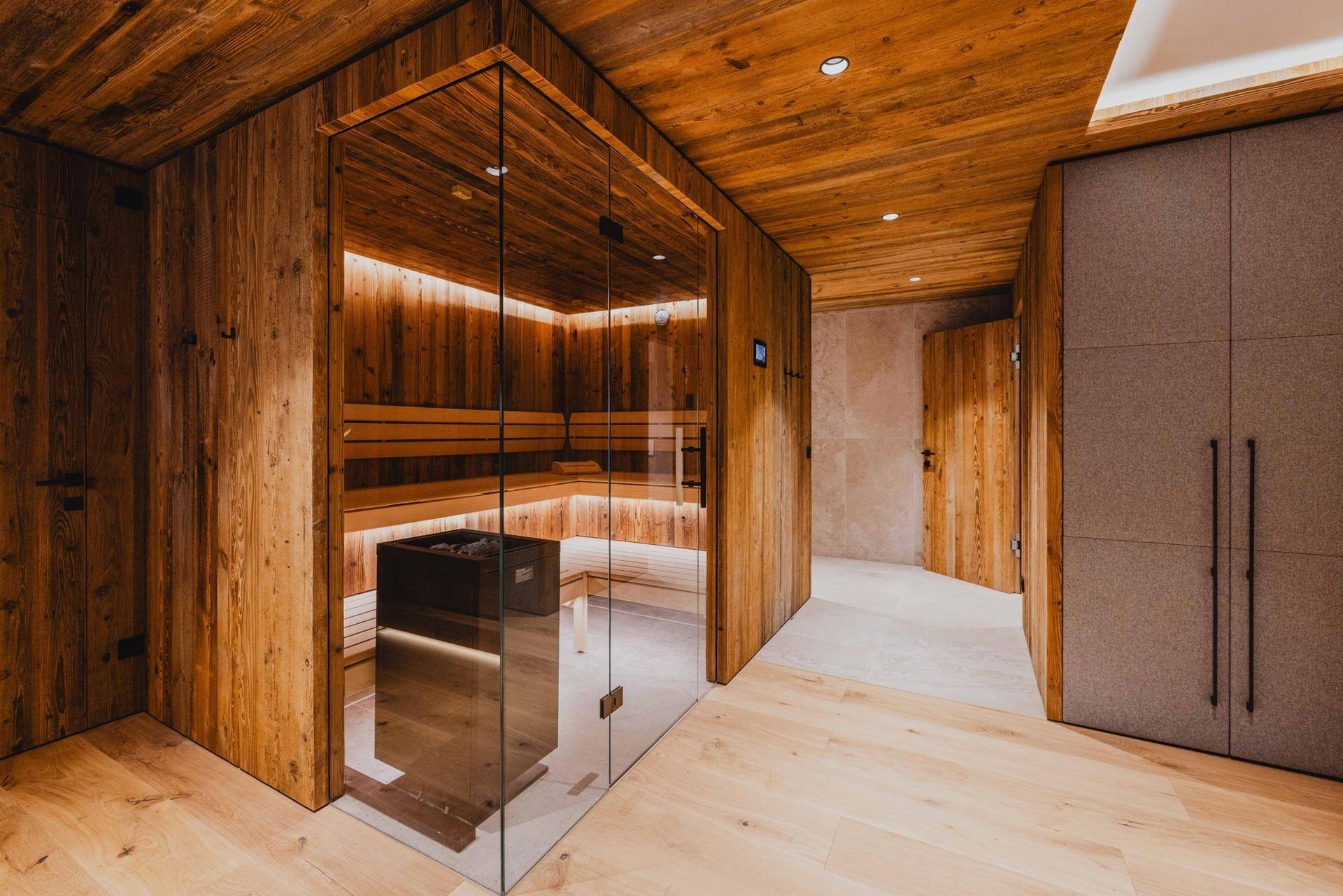 Moderner Wellnessbereich mit Glas-Sauna, Holzvertäfelung und integrierten Schränken.