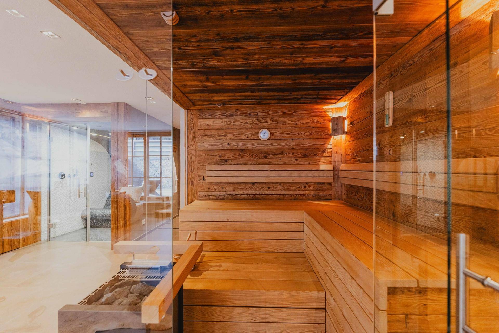 Geräumige Holzsauna mit Bänken und Glasfront, Teil eines luxuriösen Wellnessbereichs.