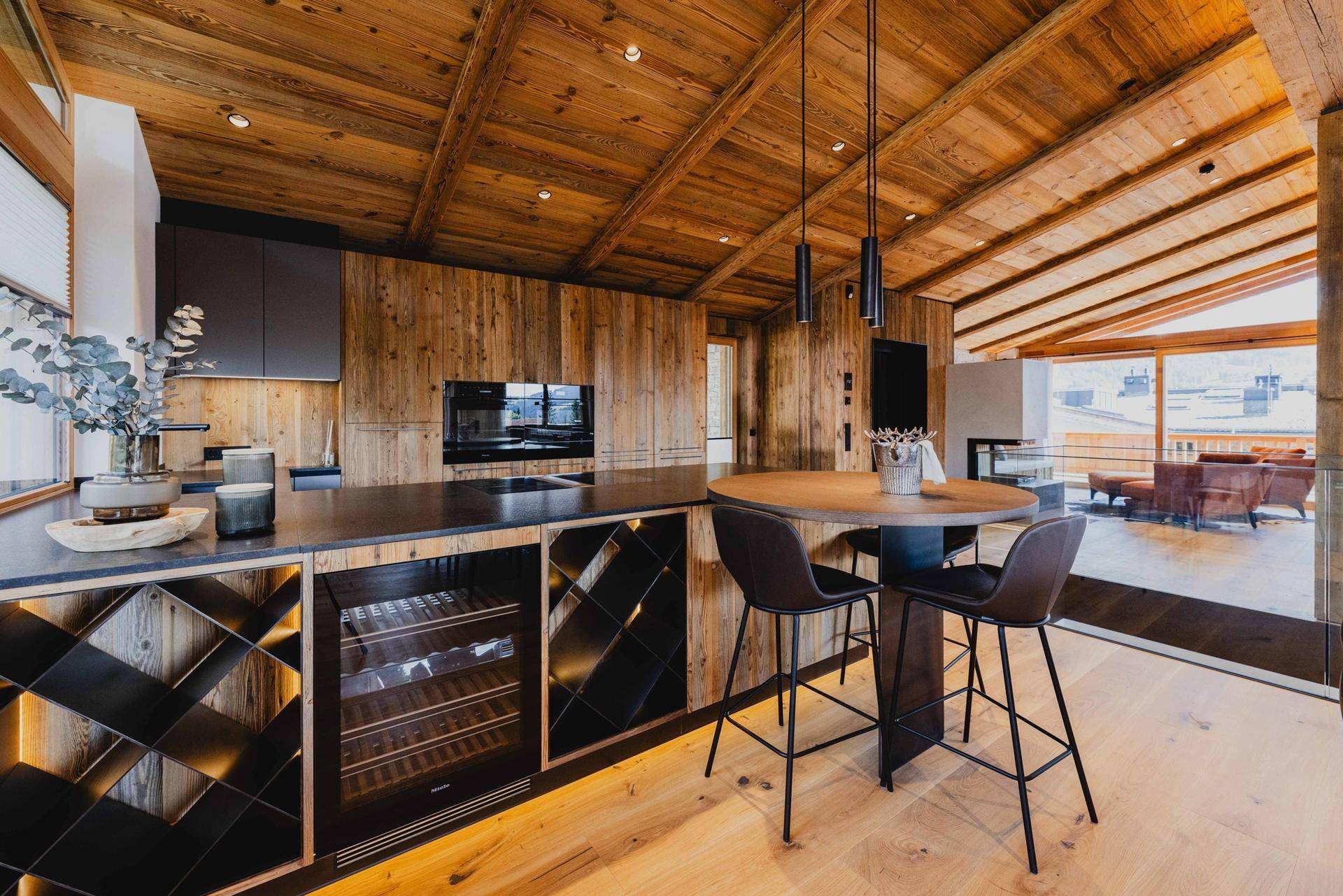 Moderne Holzküche mit dunklen Arbeitsplatten, integriertem Weinkühler und gemütlicher Frühstücksbar.