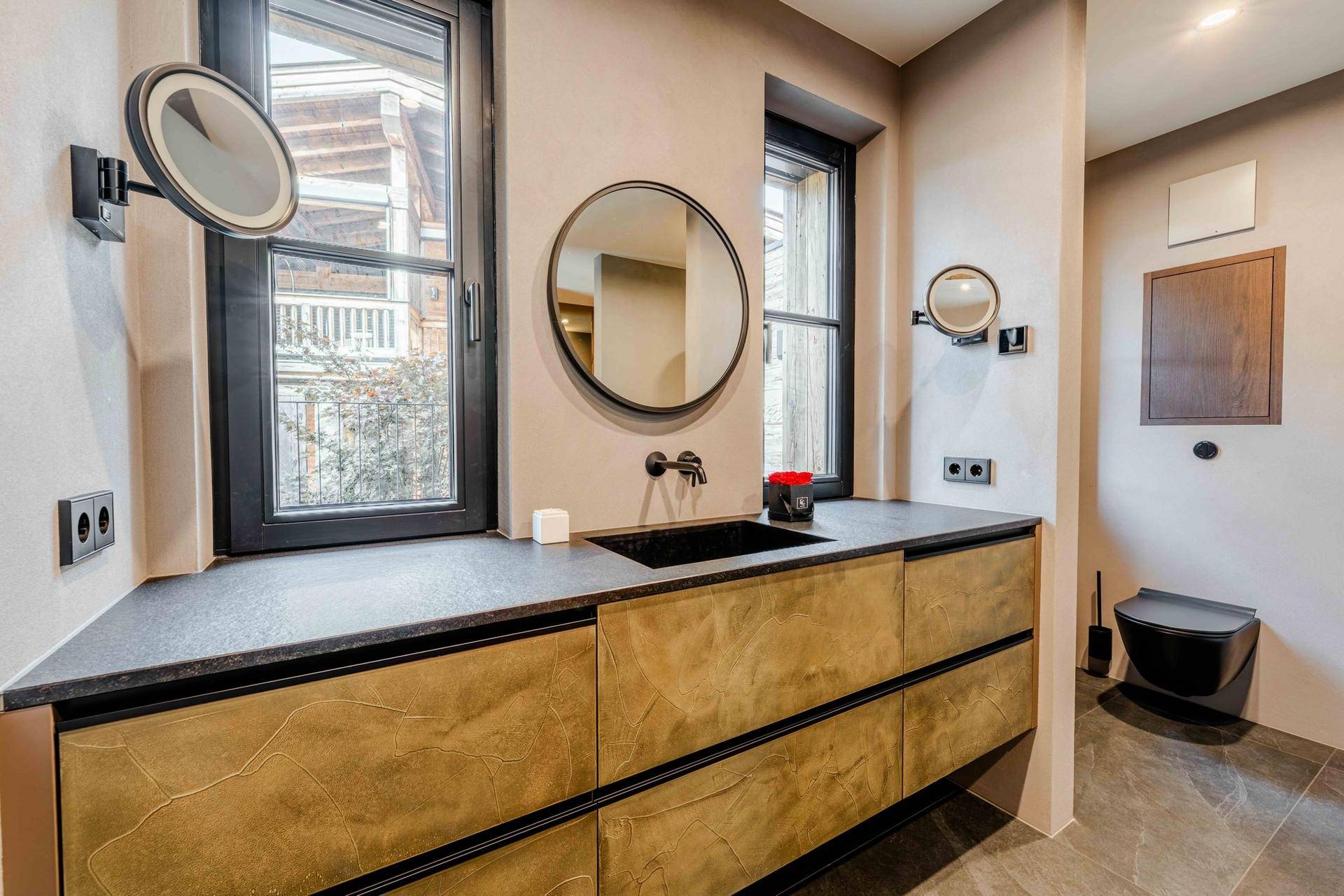 Modernes Badezimmer mit Doppelwaschbecken, dunklen Armaturen und großen Fenstern.