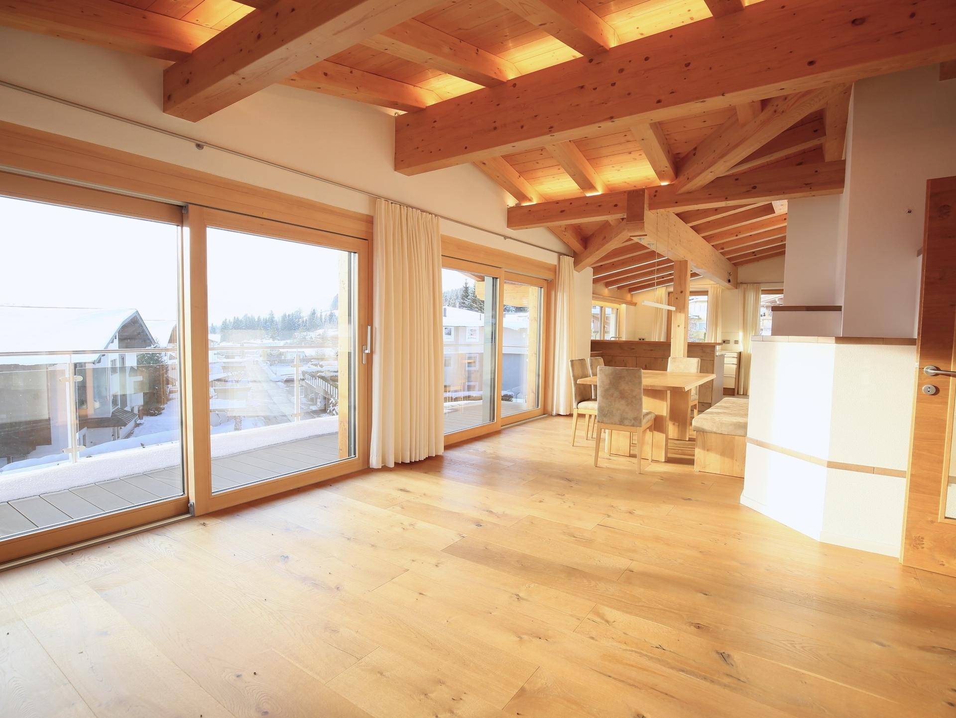 Heller Wohn- und Essbereich mit Holzbalkendecke, Parkettboden und Zugang zum Balkon.