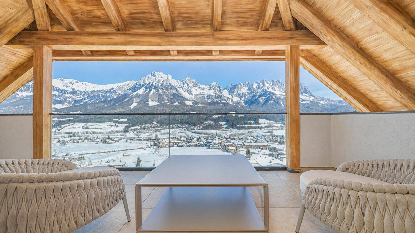 Gemütlicher Wohnbereich im Dachgeschoss mit Holzbalken und atemberaubendem Bergblick.