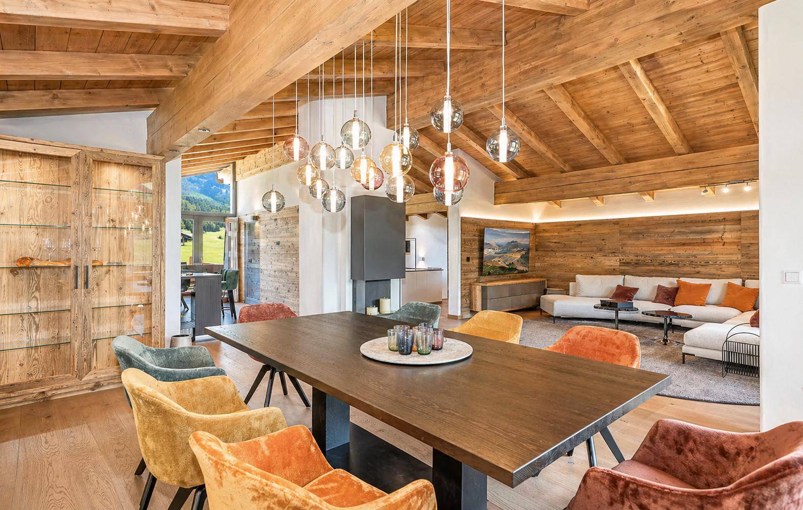 Eleganter Essbereich mit Holztisch, farbigen Stühlen und moderner Beleuchtung.