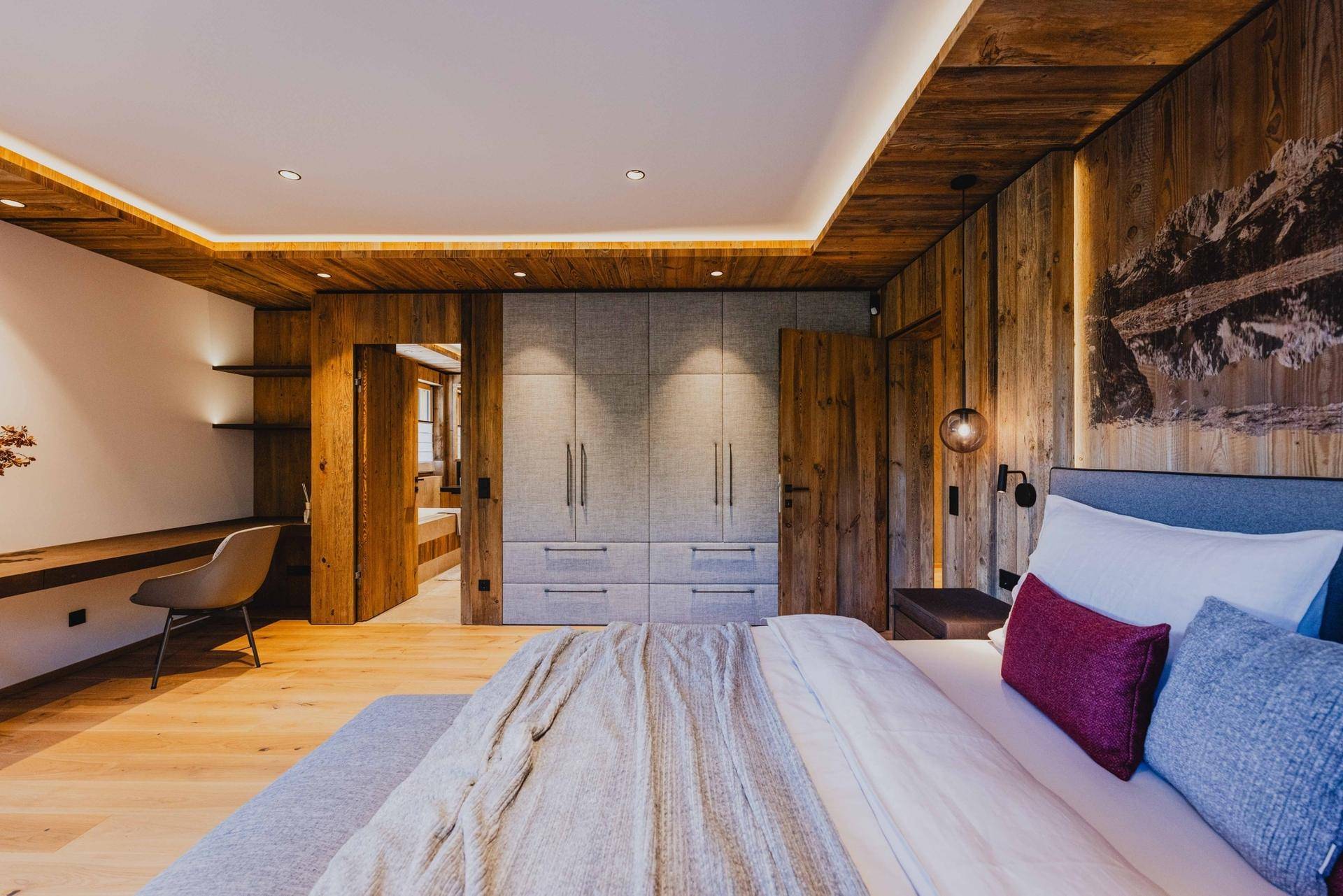 Stilvolles Schlafzimmer mit Holzboden, Einbauschränken und Wandkunst über dem Bett.