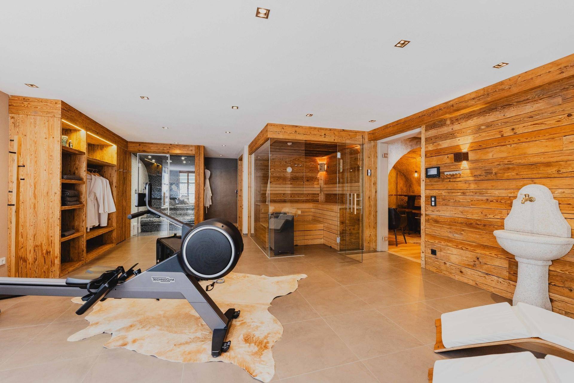 Exklusiver Wellnessbereich mit Sauna, Fitnessgeräten und Holzelementen für Entspannung und Training.