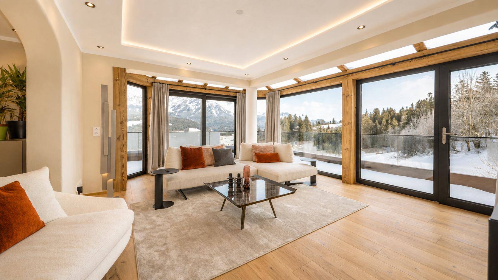 Helles Wohnzimmer mit großen Fenstern, Holzboden und Panoramablick auf die Berge.