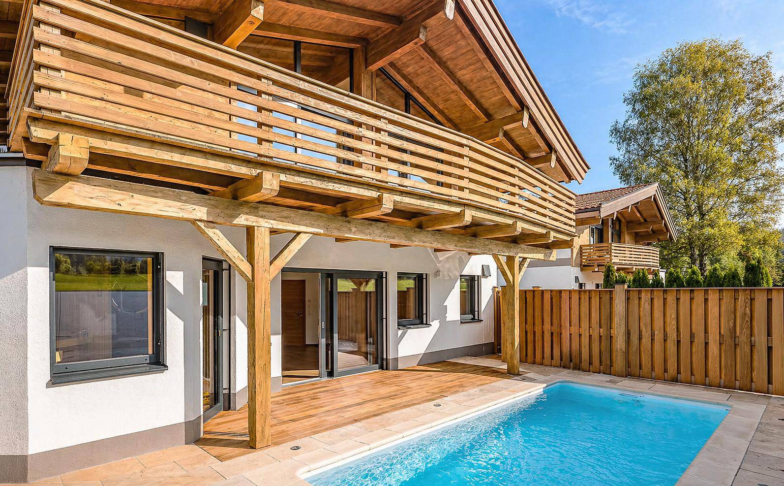 Außenbereich des Chalets mit privatem Pool, Holzterrasse und Balkon.