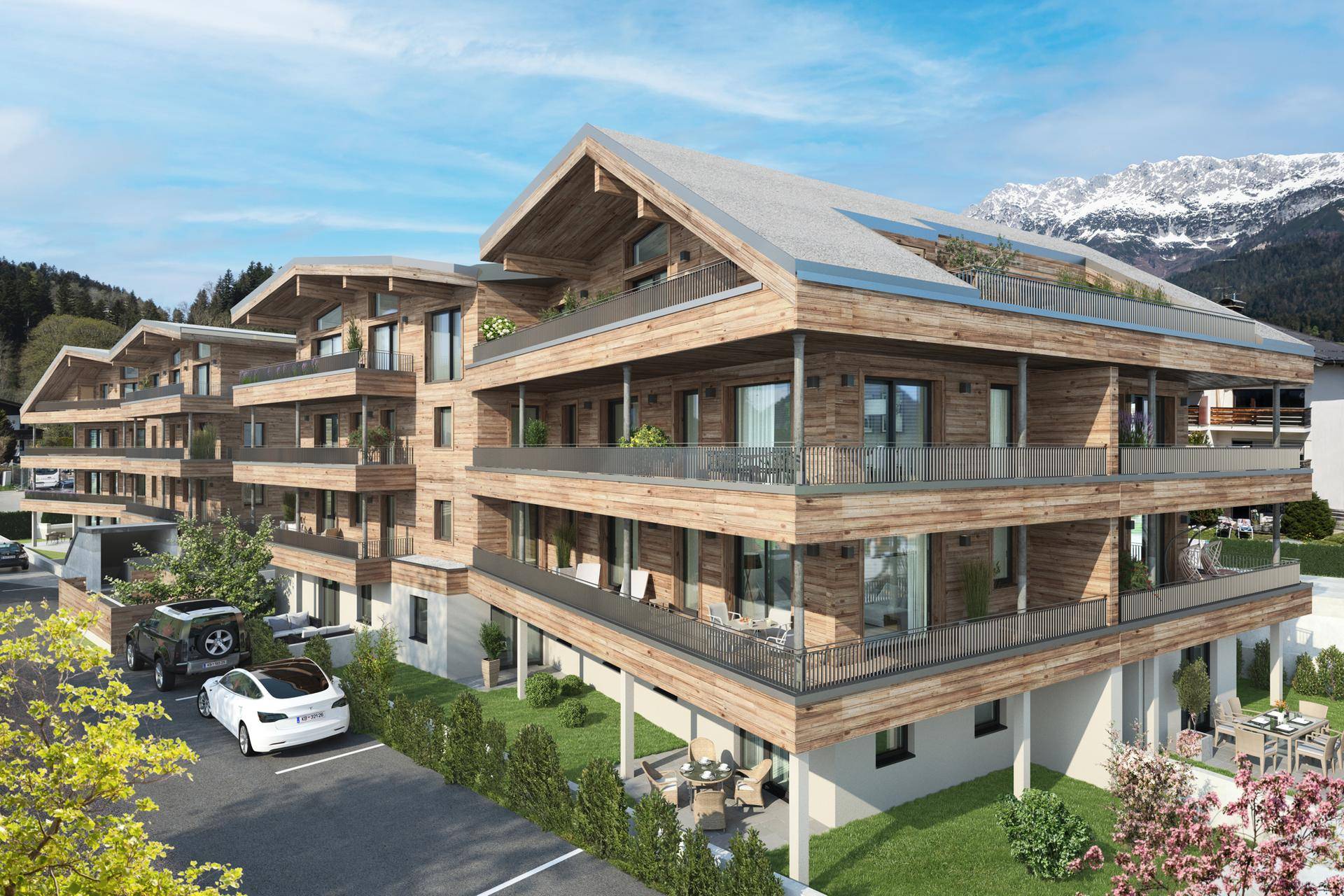 Gesamtansicht der modernen Wohnanlage mit Parkplätzen und Bergblick in sonniger Lage.