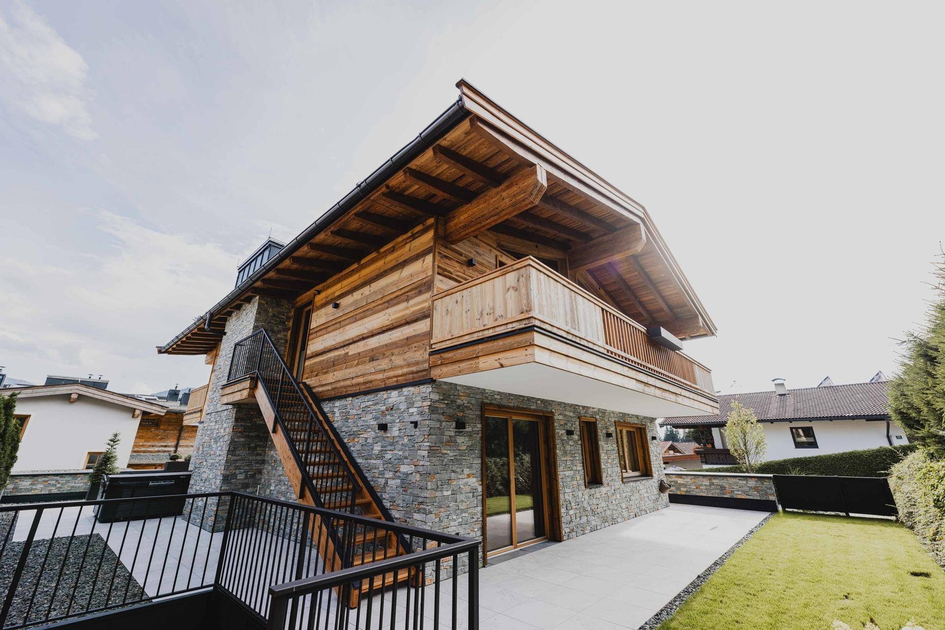 Charmantes Chalet mit Holz- und Steinfassade, umgeben von einem grünen Garten und einer großzügigen Terrasse.