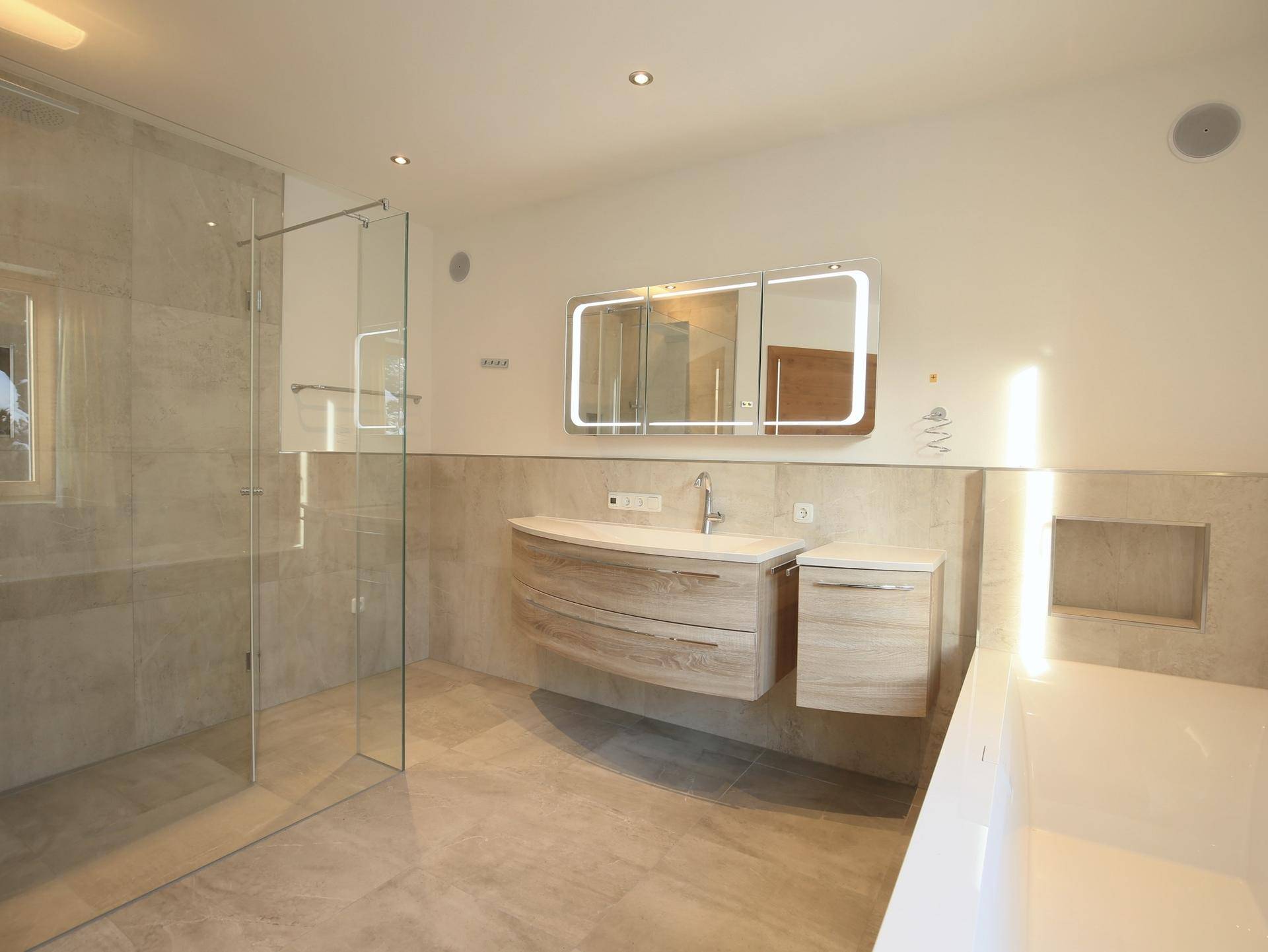 Modernes Badezimmer mit begehbarer Dusche, freistehender Badewanne und elegantem Waschtisch.