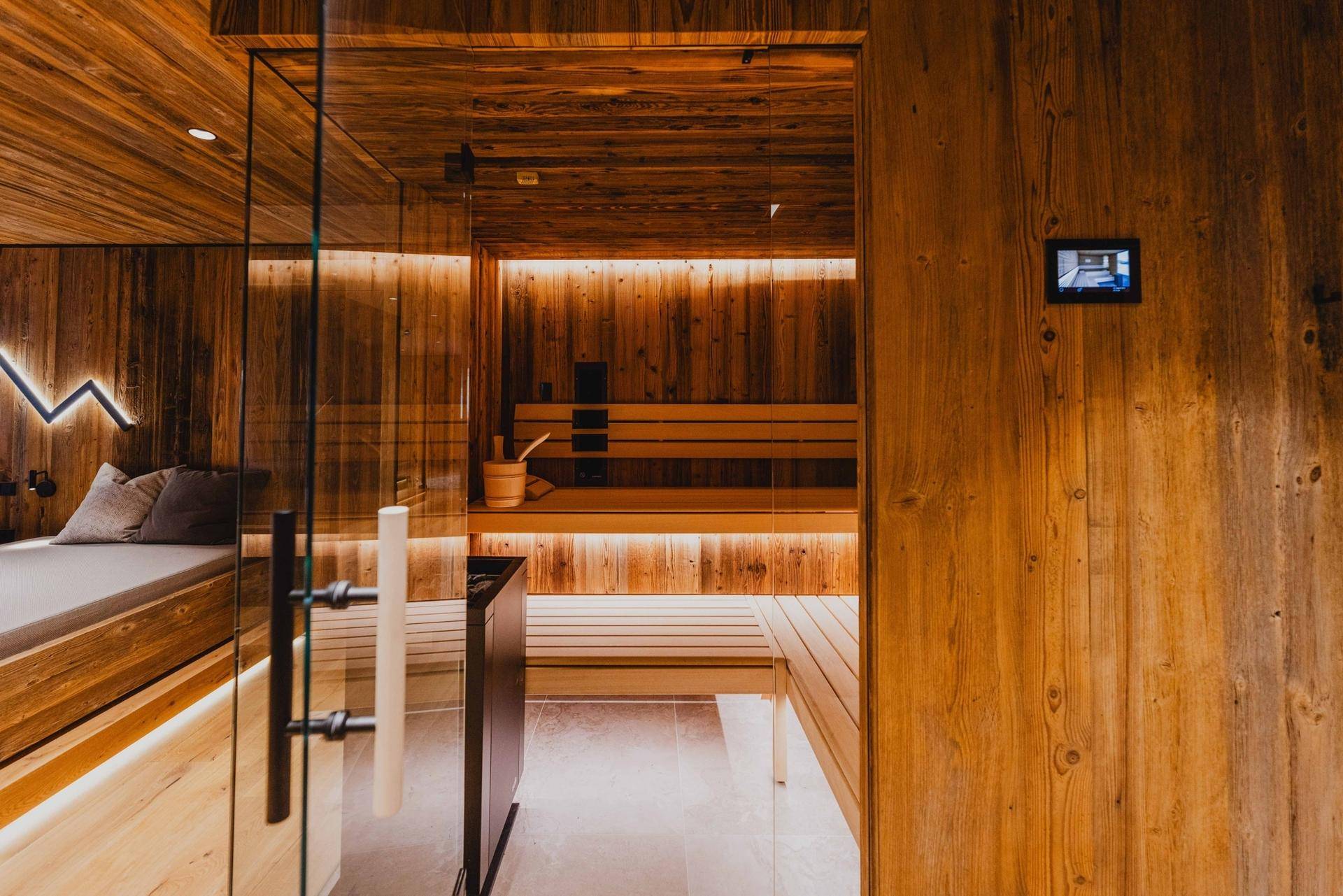 Innenansicht der modernen Sauna mit Holzbänken und indirekter Beleuchtung.