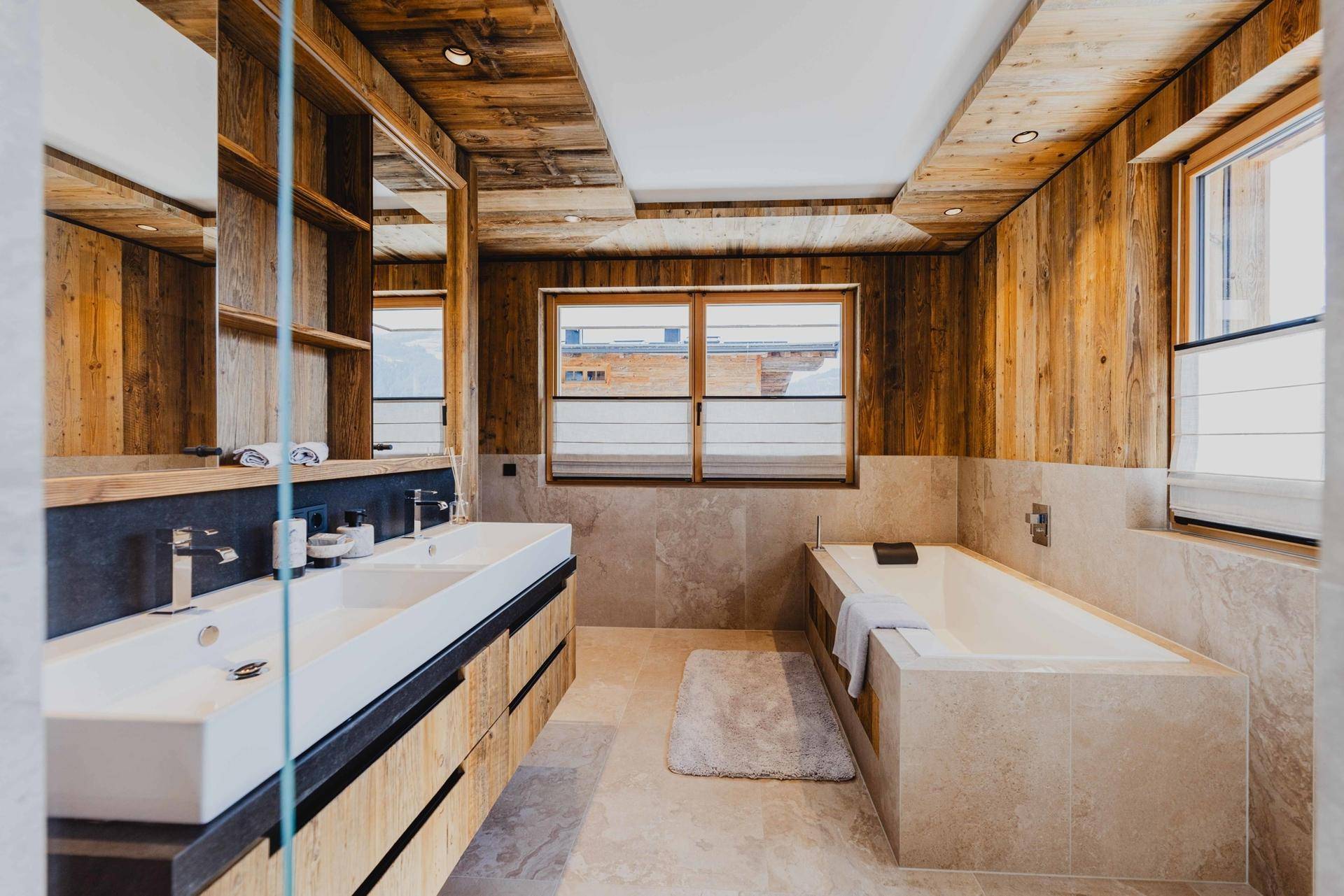 Modernes Badezimmer mit Doppelwaschbecken, Badewanne und Holzwänden für eine warme Atmosphäre.
