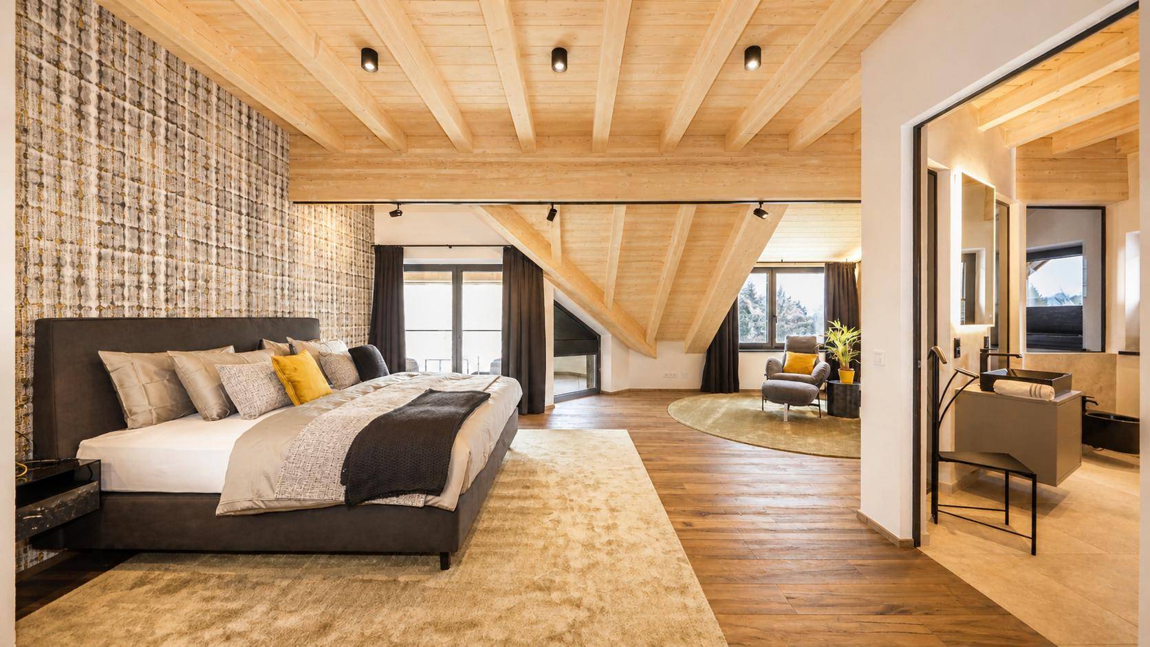Elegantes Schlafzimmer mit Holzwänden, Holzbalkendecke und Zugang zu einem offenen Bad.