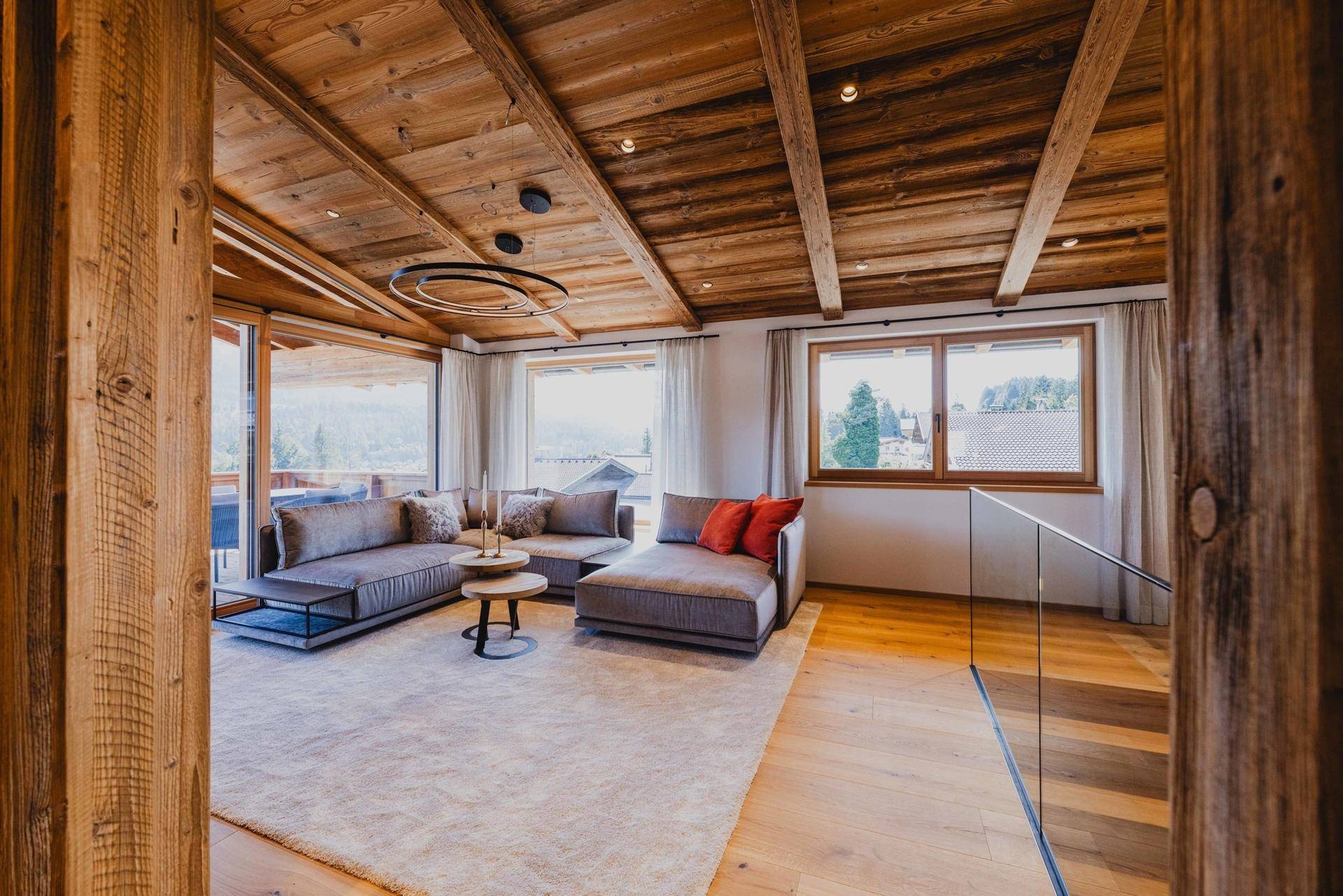 Gemütliches Wohnzimmer mit Holzbalkendecke, bequemen Sofas und Zugang zu einem Balkon.