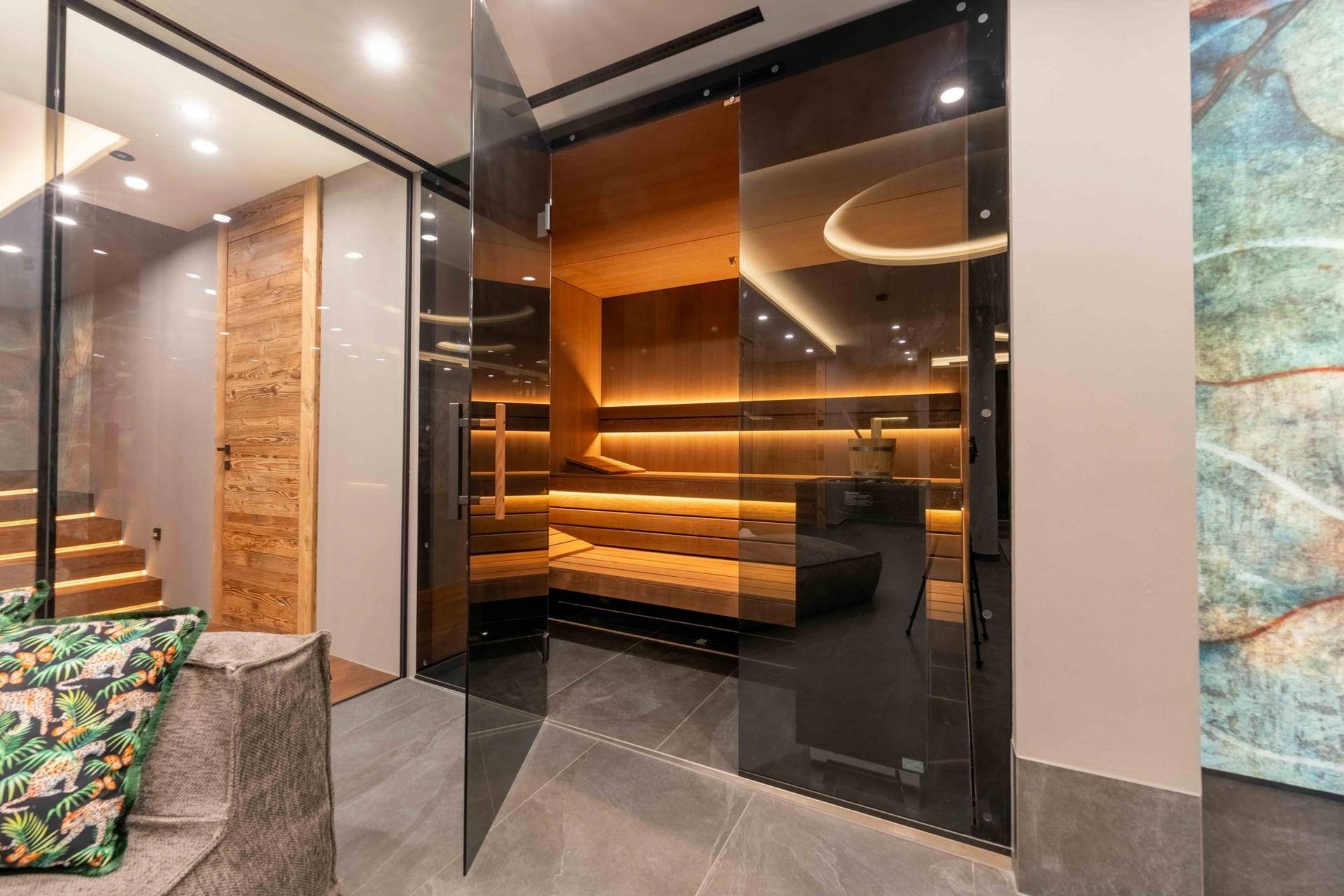 Luxuriöse Sauna mit Holzbänken und stimmungsvoller Beleuchtung, Teil eines Wellnessbereichs.