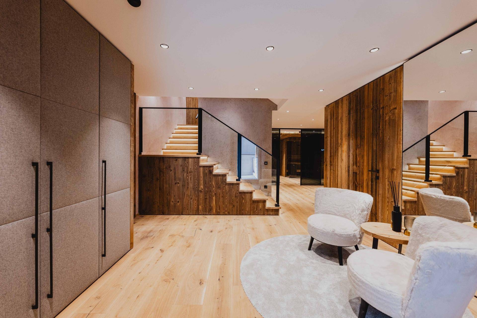 Heller Eingangsbereich mit Holzvertäfelung, Einbauschränken und moderner Treppe.