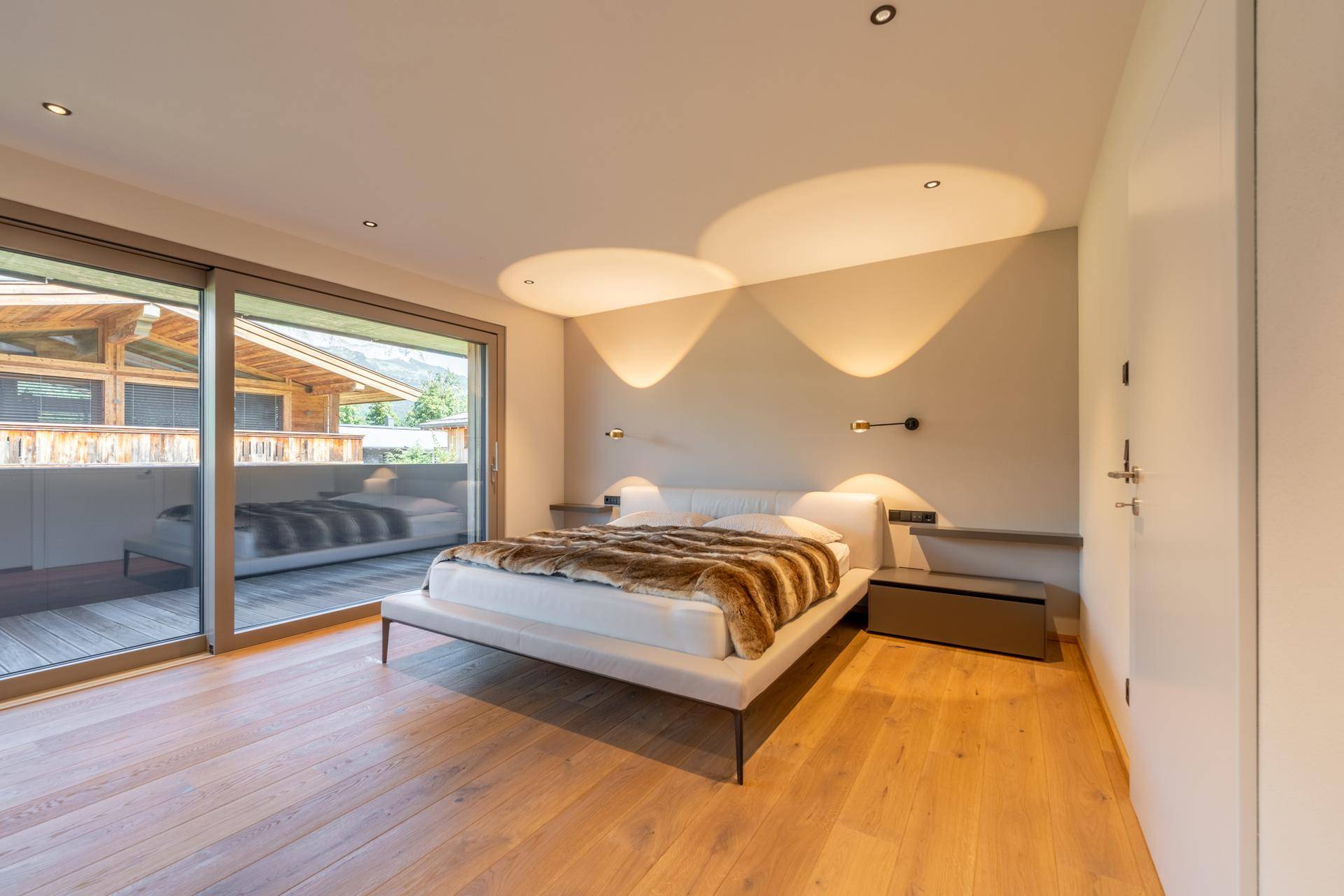 Helles Schlafzimmer mit modernem Bett, Holzboden und direktem Zugang zu einem Balkon.