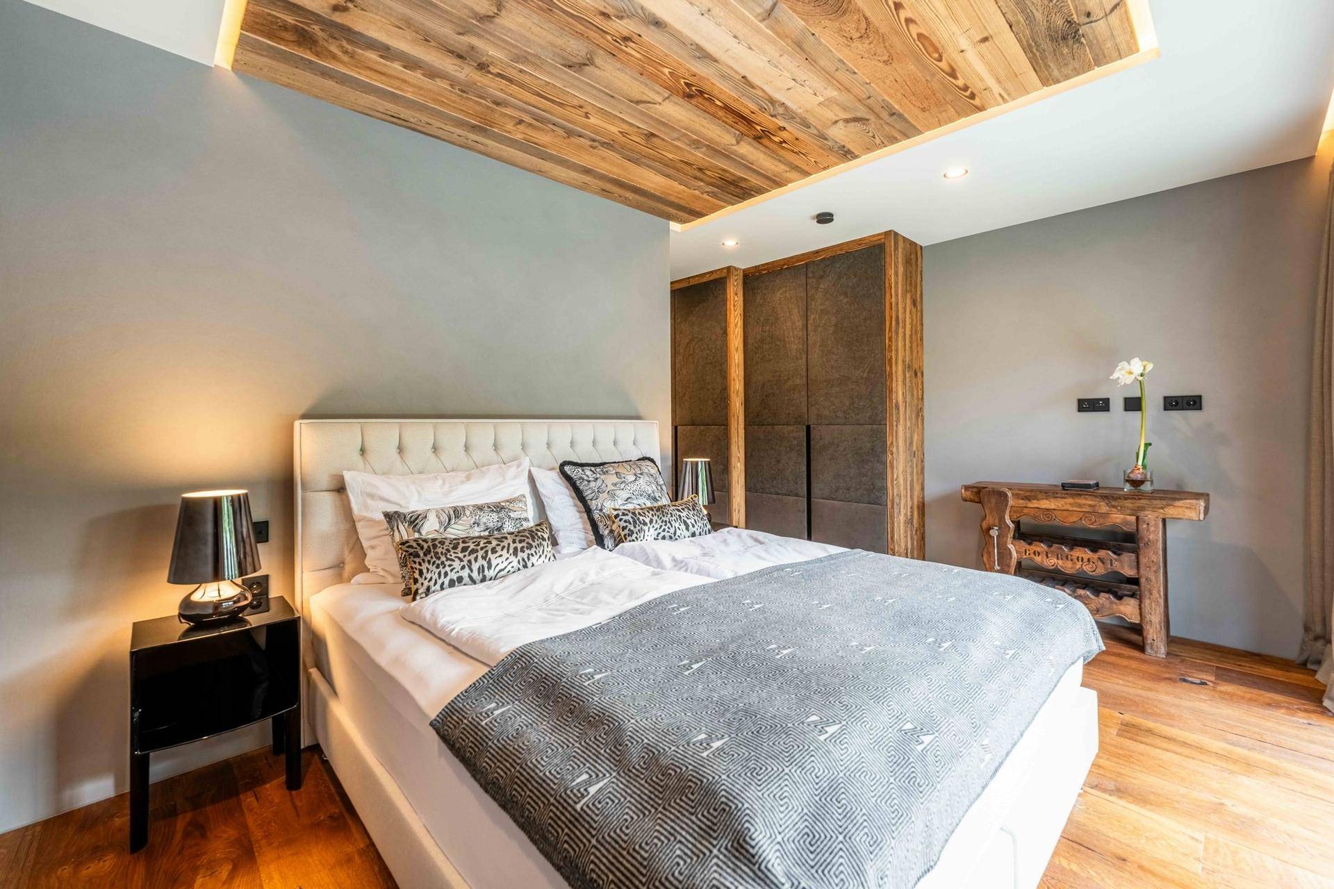 Modernes Schlafzimmer mit Holzboden, gepolstertem Bett und indirekter Deckenbeleuchtung.