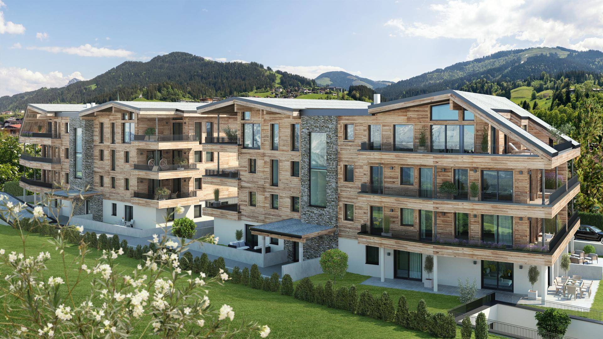 Moderne Wohnanlage mit Holzfassade, großen Balkonen und grüner Umgebung in den Bergen.