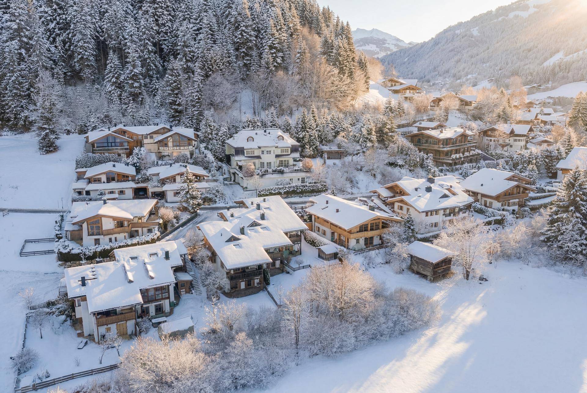 Luftaufnahme einer Siedlung von Häusern in einer verschneiten Berglandschaft.