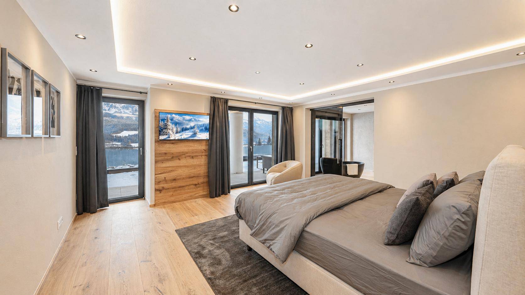 Helles Schlafzimmer mit Balkonzugang, Holzboden und Blick auf die verschneite Landschaft.