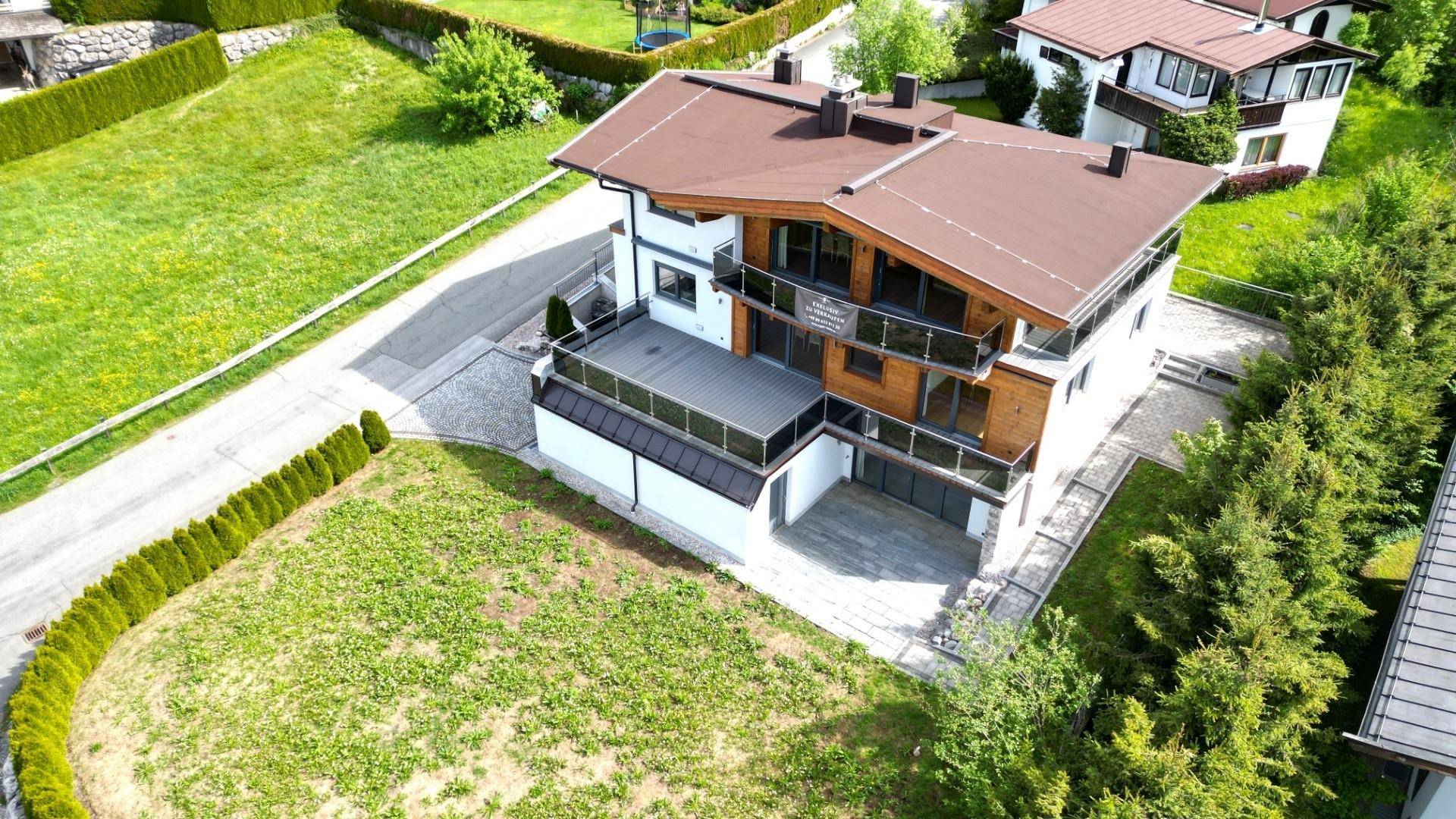 Vogelperspektive des modernen Wohnhauses mit großem Grundstück und umliegender Naturlandschaft.