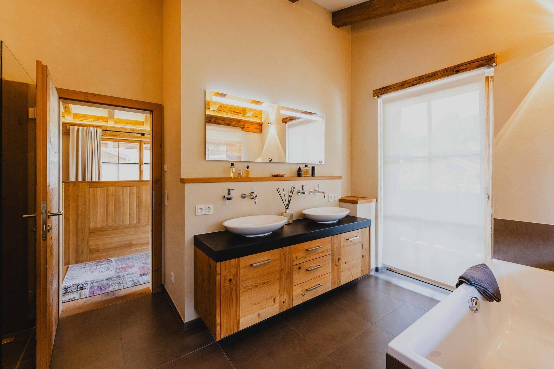 Modernes Badezimmer mit Doppelwaschbecken, Badewanne und großem Fenster für natürliches Licht.
