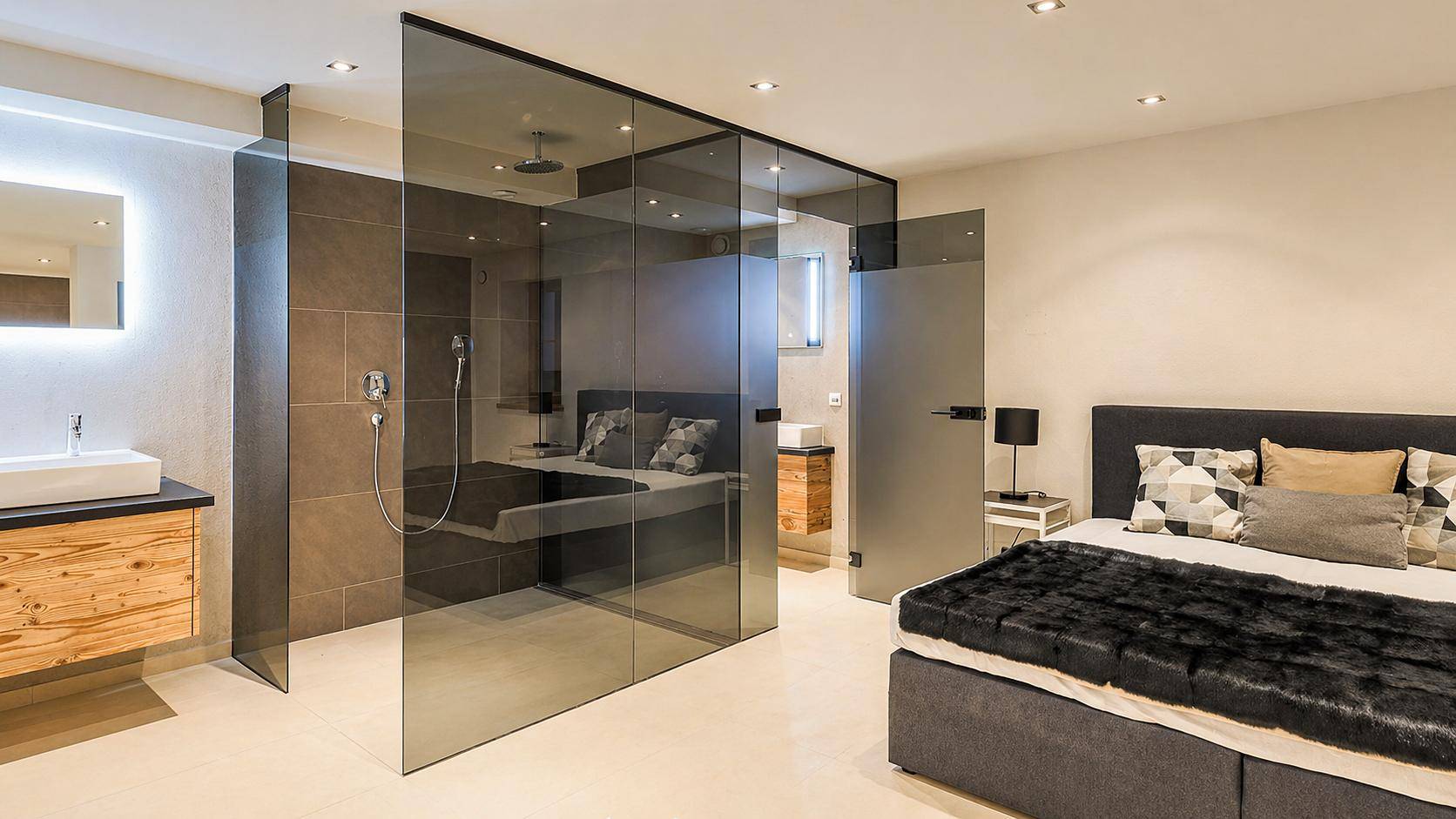 Modernes Schlafzimmer mit integriertem Badezimmerbereich, Glaswänden und Doppelbett.