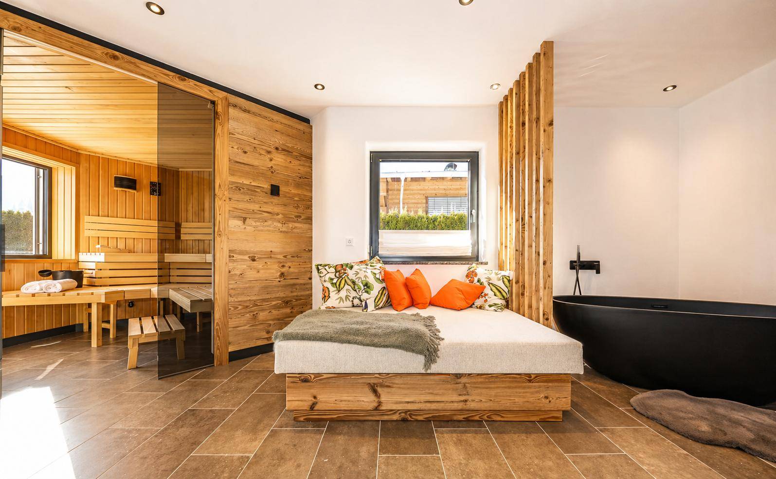 Entspannender Wellnessbereich mit Sauna, Liege und freistehender Badewanne.