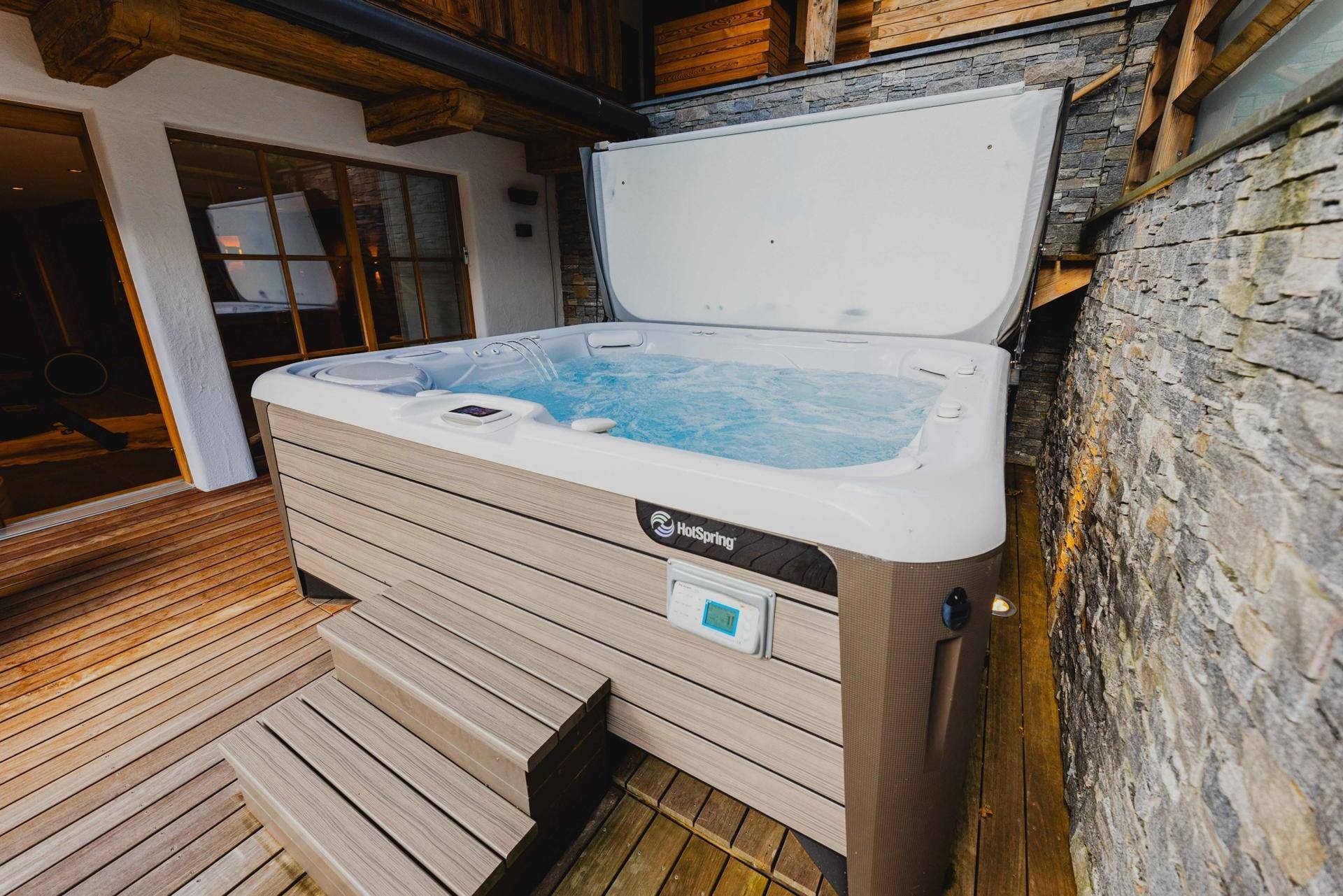 Außenwhirlpool auf einer Holzterrasse, ideal für Entspannung im Freien mit Blick auf die Umgebung.