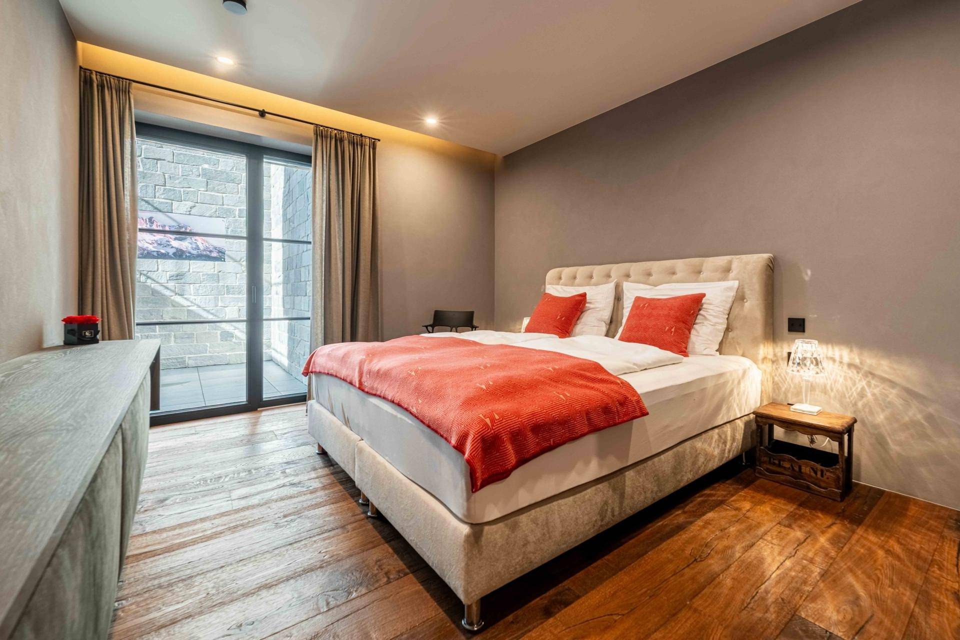 Gemütliches Schlafzimmer mit Holzboden, großem Bett und Blick auf den Außenbereich.