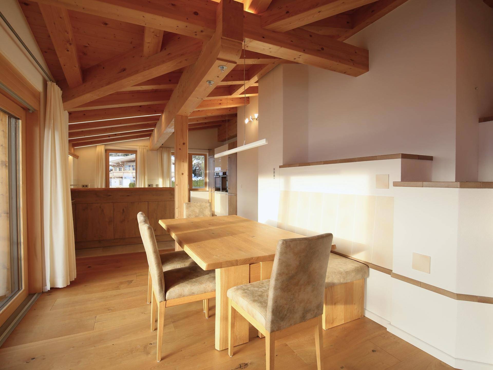Gemütlicher Essbereich mit Holztisch, eingebauter Sitzbank und sichtbaren Holzbalken an der Decke.