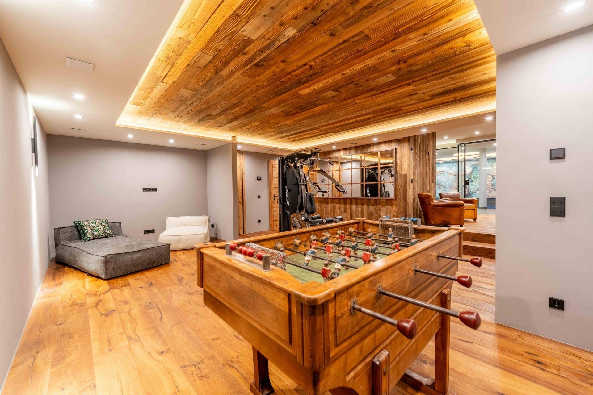 Unterhaltungsraum mit Tischfußball, Holzboden und indirekter Deckenbeleuchtung.