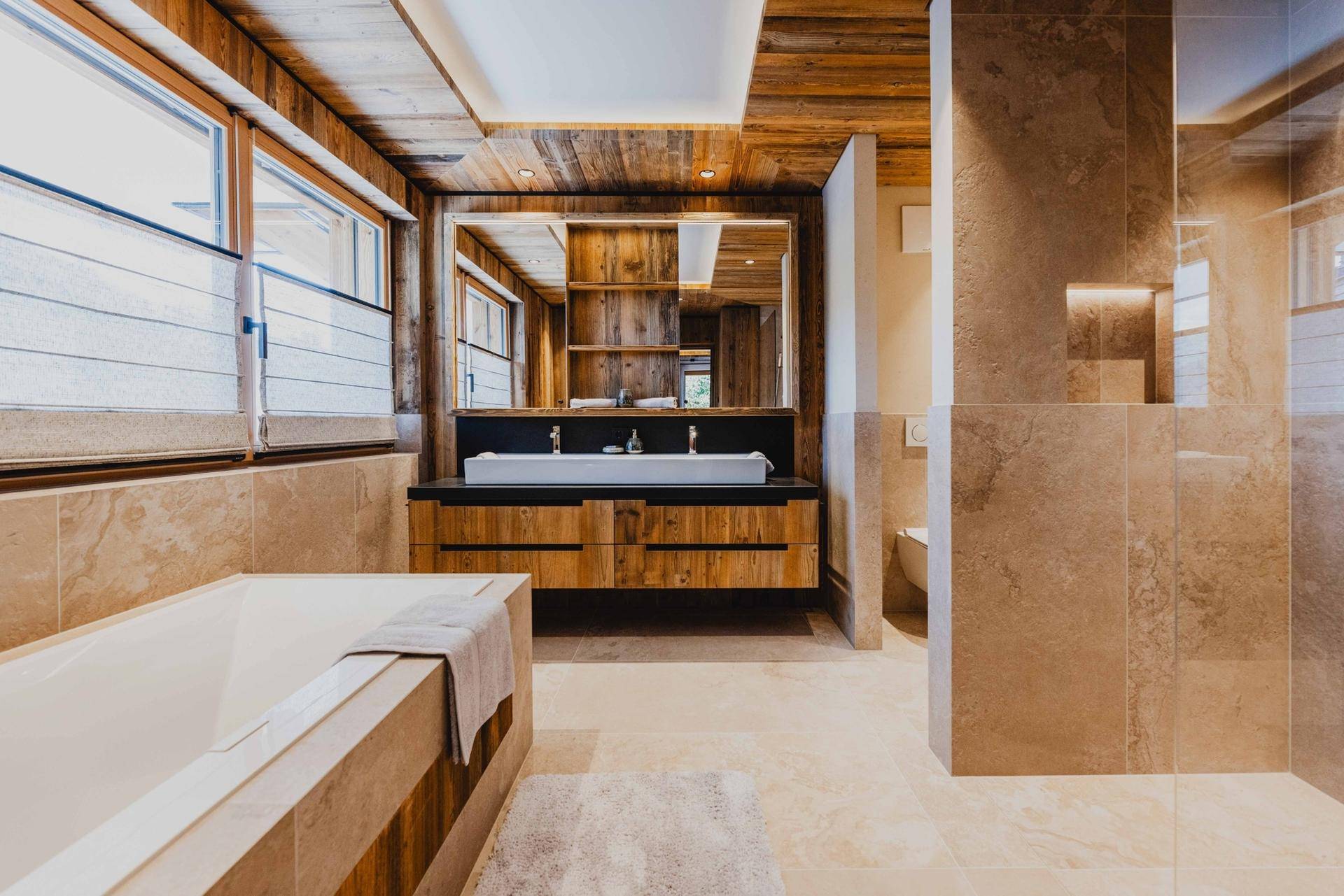 Modernes Badezimmer mit Doppelwaschbecken, Badewanne und Holzvertäfelung.
