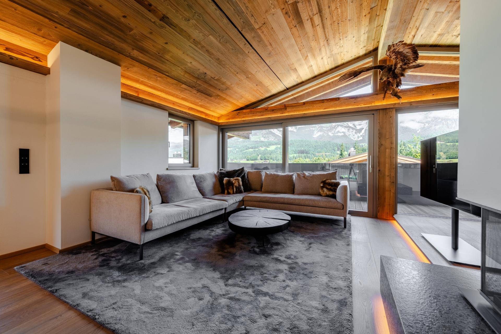 Gemütliches Wohnzimmer mit großem Sofa, modernem Kamin und beeindruckendem Bergblick.