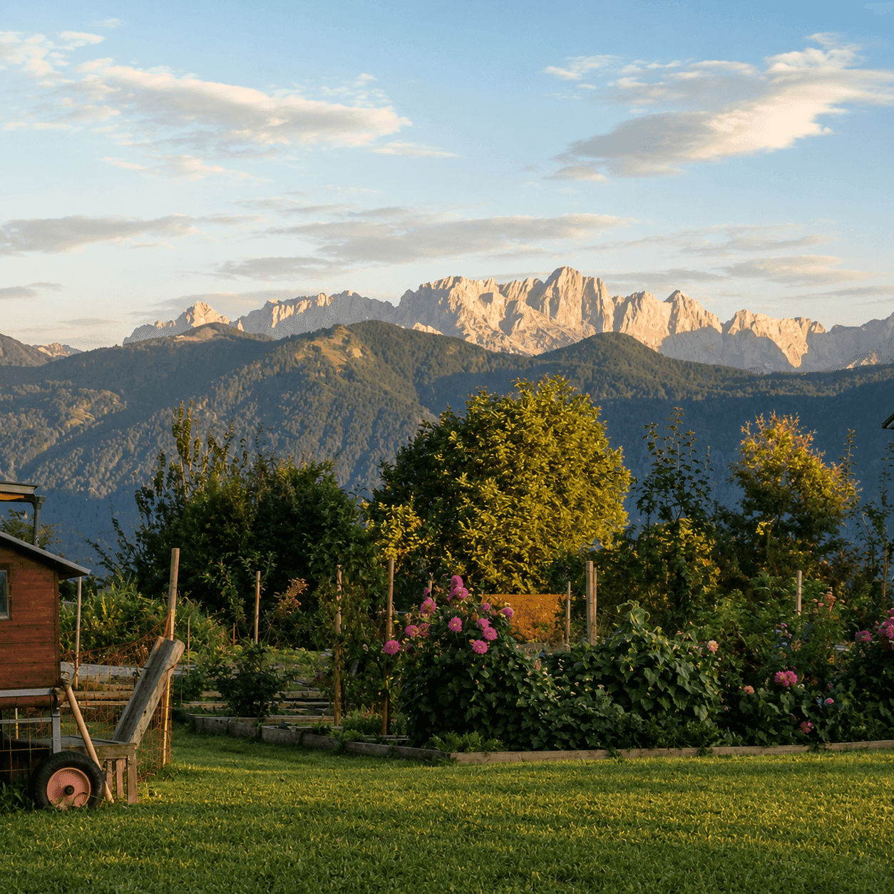 Malerischer Garten mit Blumen und einem Schuppen vor einer beeindruckenden Bergkulisse bei Sonnenuntergang.