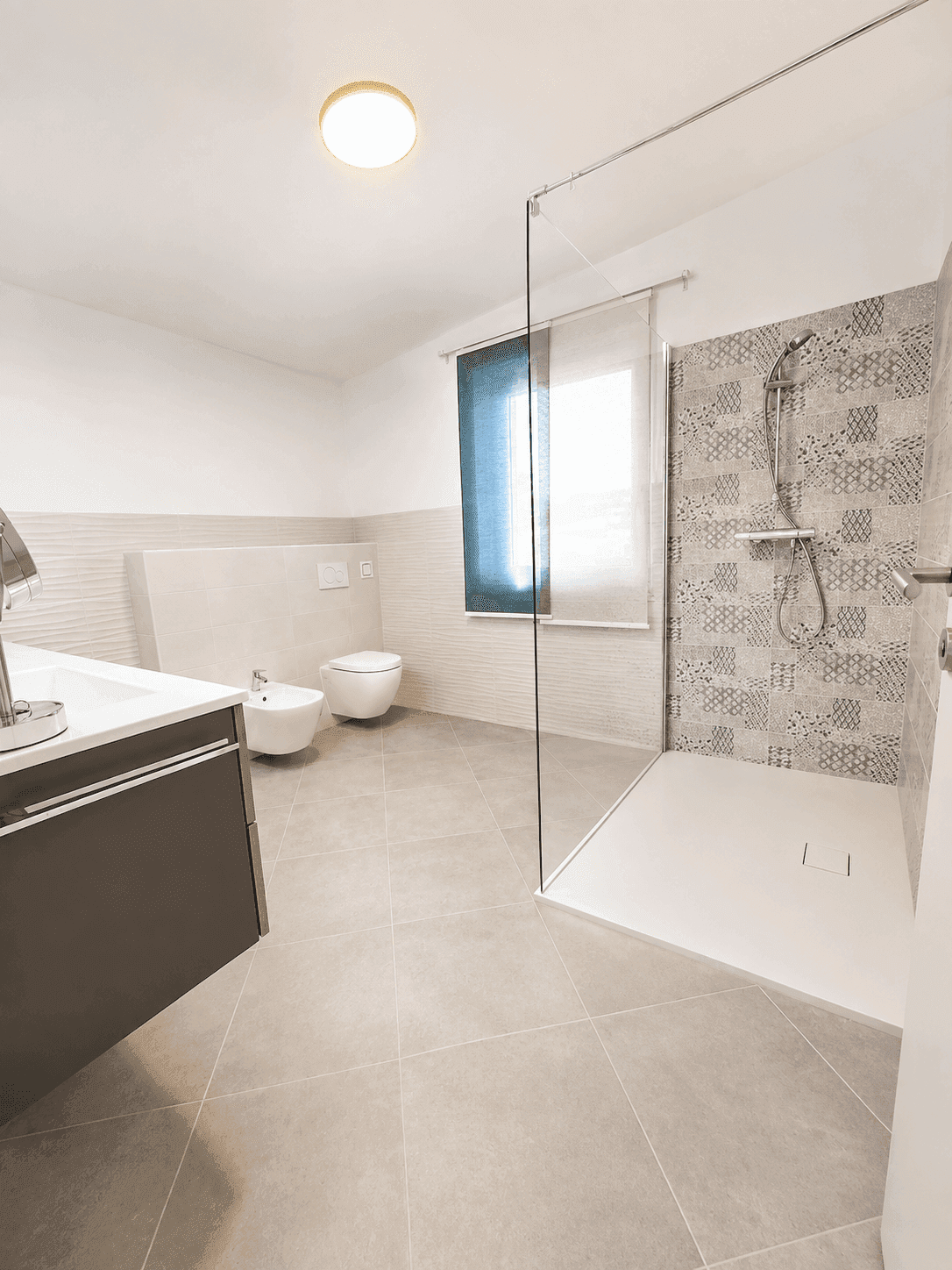 Helles Badezimmer mit begehbarer Dusche, Bidet, WC und Fenster für Tageslicht.