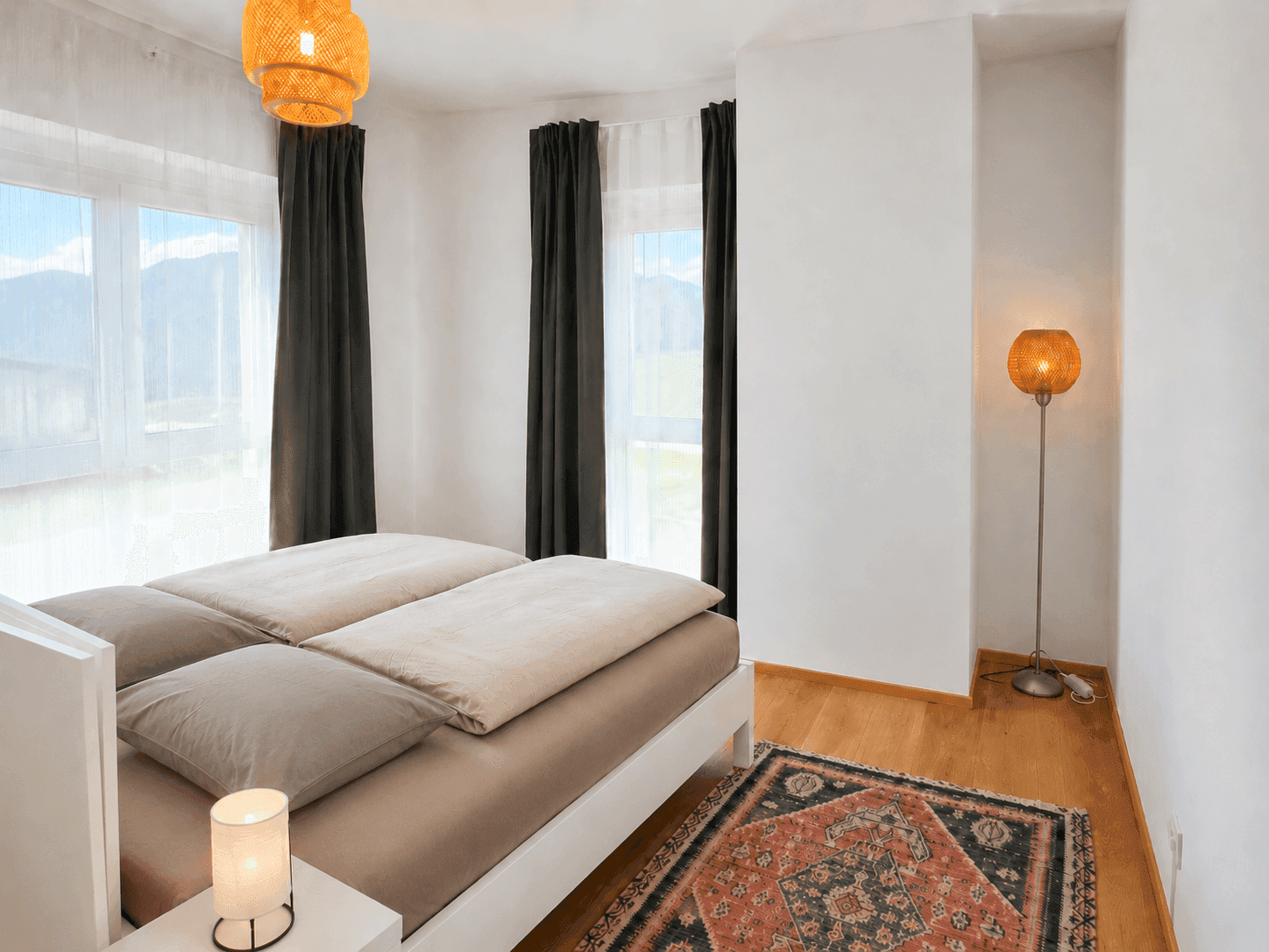 Gemütliches Schlafzimmer mit Doppelbett, Holzboden und weitem Blick auf die Berge.