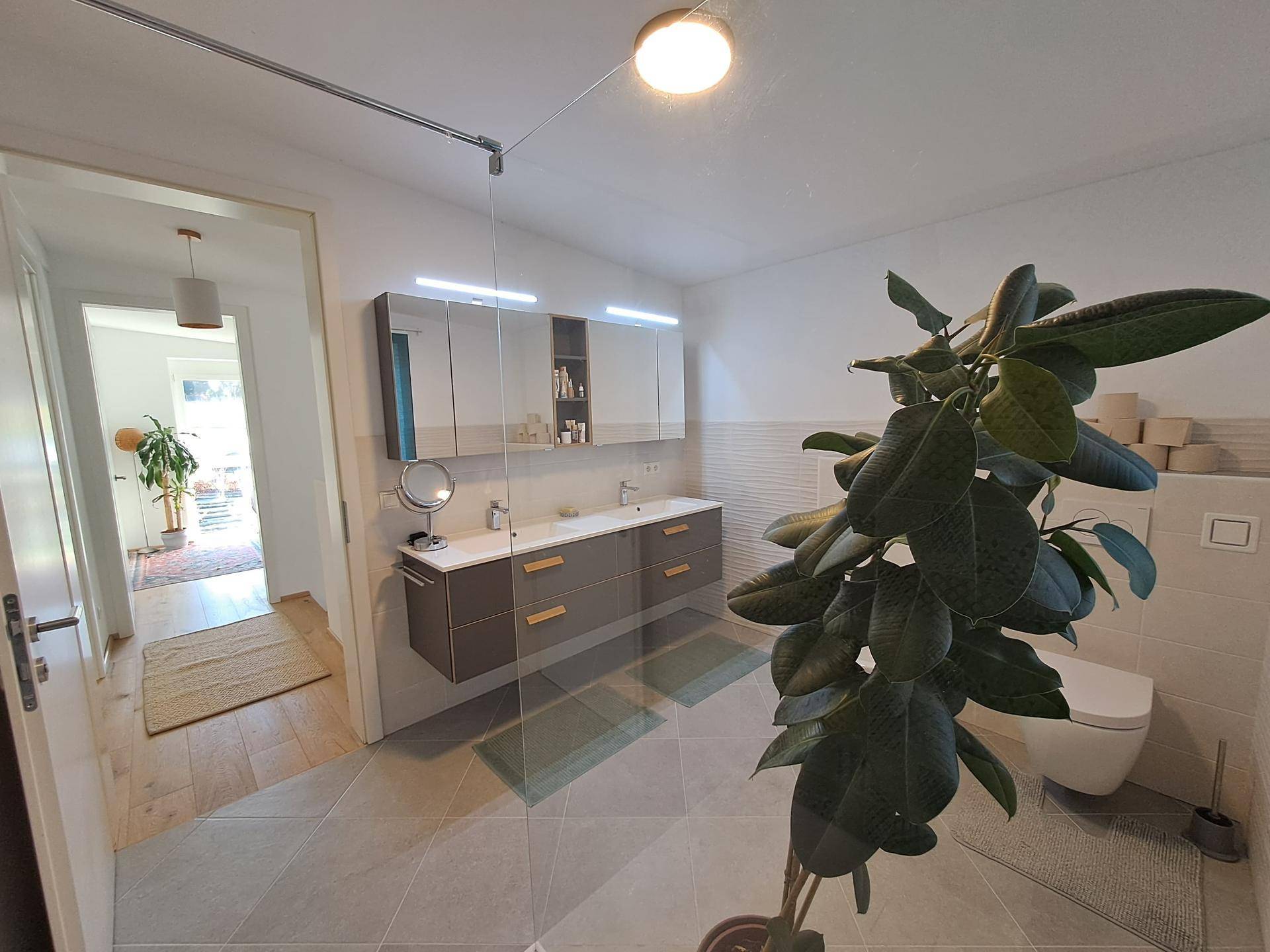 Modernes Badezimmer mit begehbarer Dusche, Doppelwaschbecken und Wand-WC.