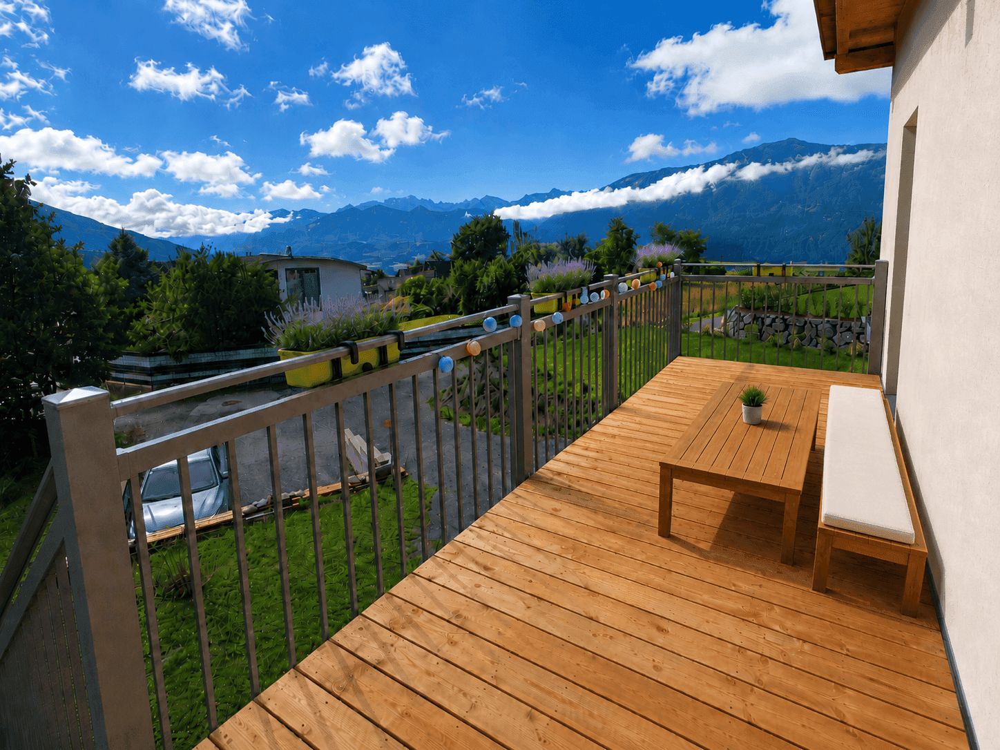 Geräumiger Holzbalkon mit Sitzgelegenheiten und weitem Blick auf die umliegende Berglandschaft.