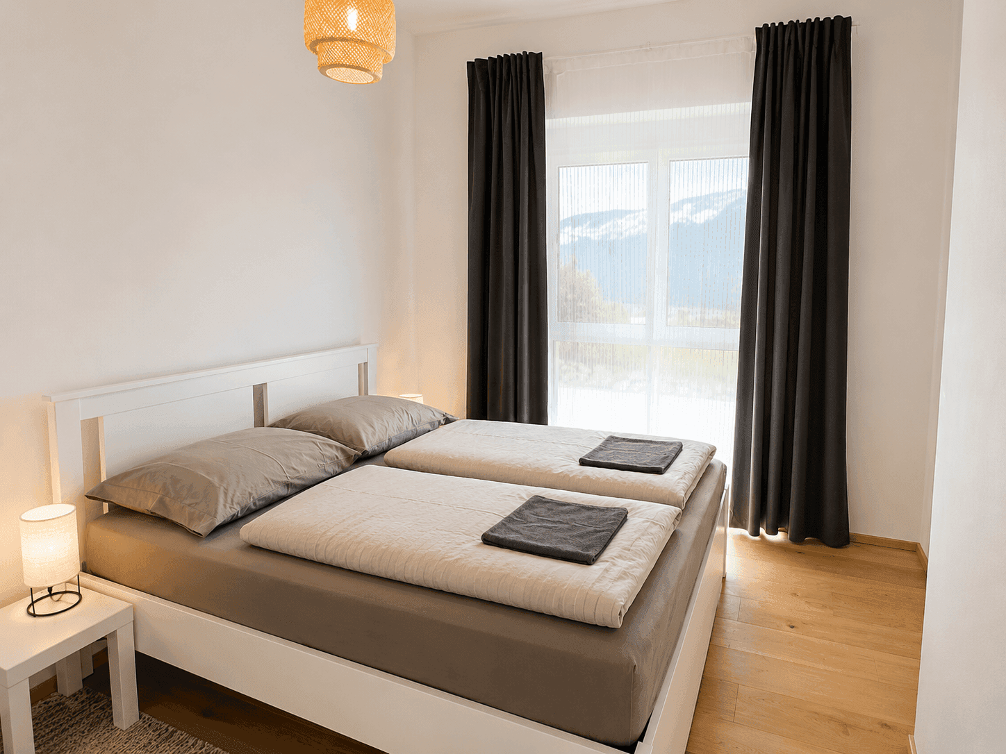 Helles Schlafzimmer mit Doppelbett, Holzboden und Panoramablick auf die umliegende Bergwelt.