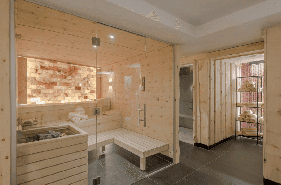 Helle Sauna mit Holzverkleidung, Glasfront und Salzsteinwand für entspannende Momente.