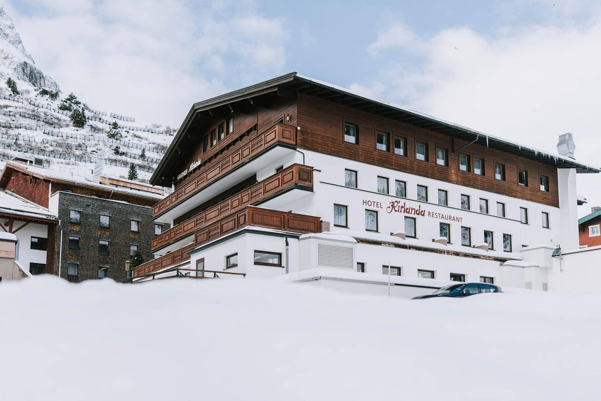 Das Hotel Kirlana im Winter, umgeben von tiefem Schnee und schneebedeckten Hängen.
