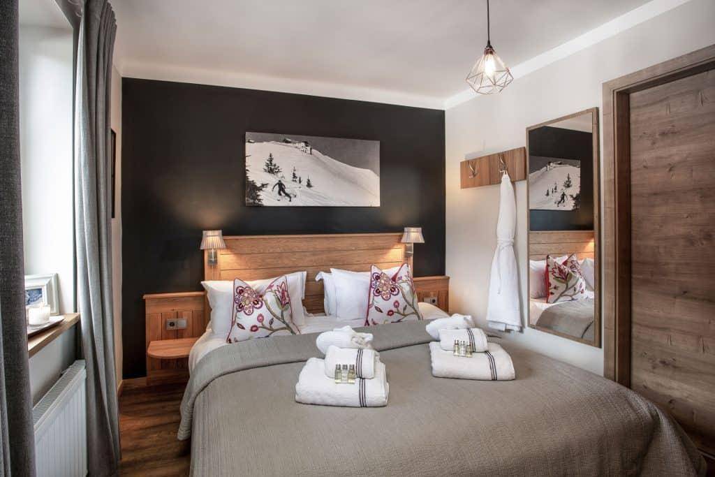 Gemütliches Schlafzimmer mit Holzbett, dunkler Wand und Spiegel, ideal für erholsame Nächte.