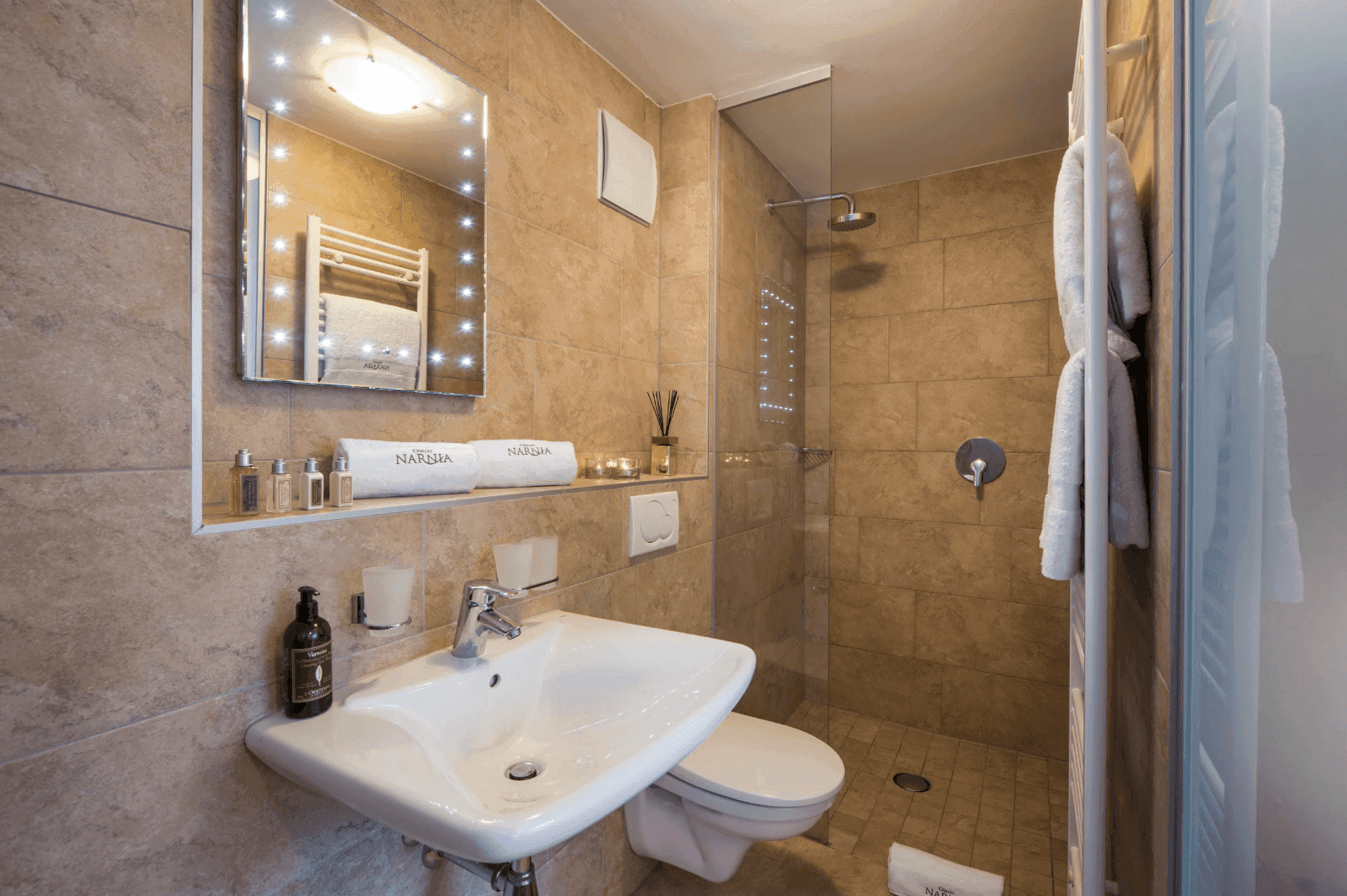 Modernes Badezimmer mit ebenerdiger Dusche, Einzelwaschbecken und beleuchtetem Spiegel.