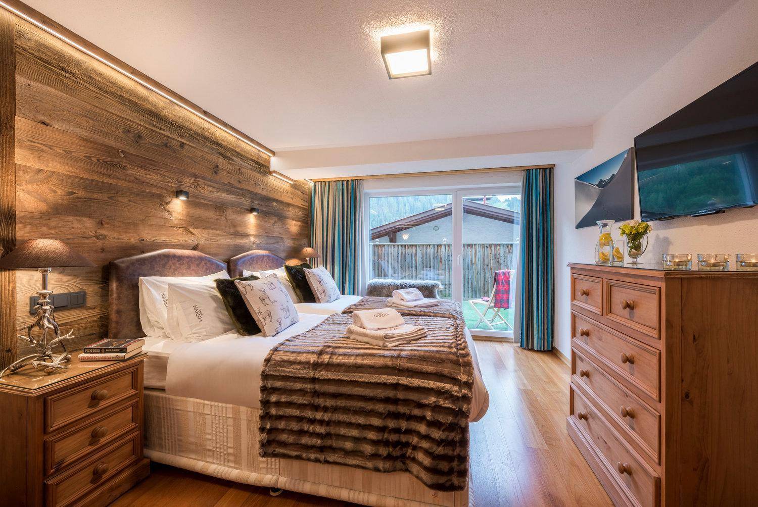 Schlafzimmer mit Holzboden, TV und direktem Zugang zu einer kleinen Terrasse oder Balkon.
