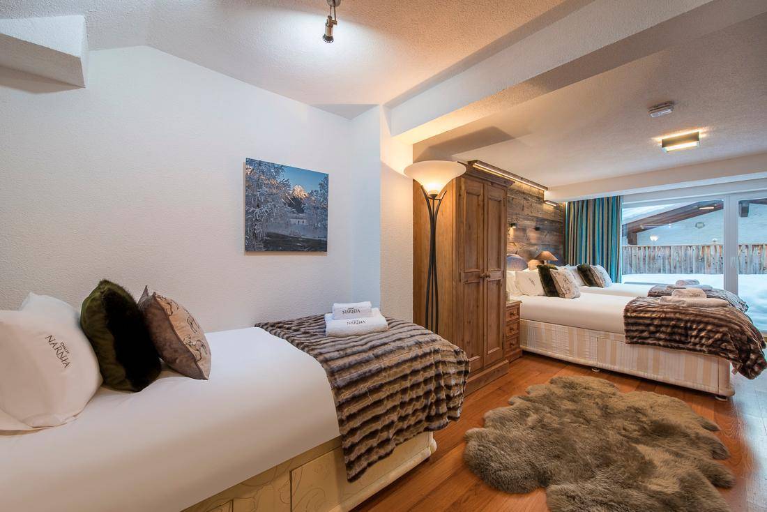 Helles Schlafzimmer mit zwei Einzelbetten, Holzboden und Blick ins Grüne.