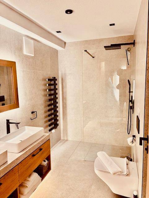 Modernes Badezimmer mit begehbarer Dusche, Doppelwaschbecken, Wand-WC und beheiztem Handtuchhalter.